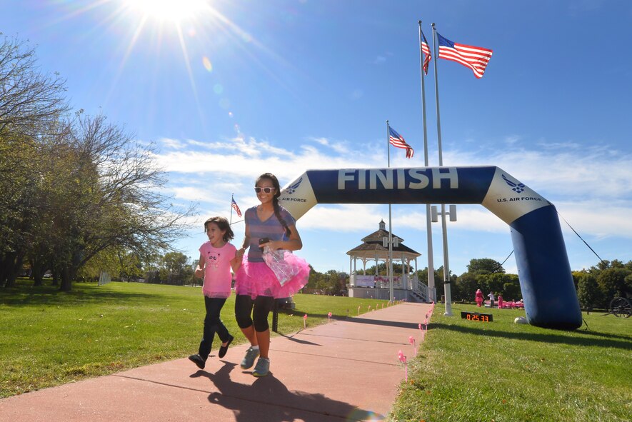 Staff Sgt. Maricris Canup, 55th Force Support Squadron field house programs and events manager, and her six-year-old daughter, Shaela, cross the finish line of the first inaugural Breast Cancer Awareness 5K Oct. 2 on the historic Offutt Air Force Base, Neb., parade grounds.  Runners from the 55th Wing and its tenant units came together for the cause.  (U.S. Air Force photo by Josh Plueger/Released)