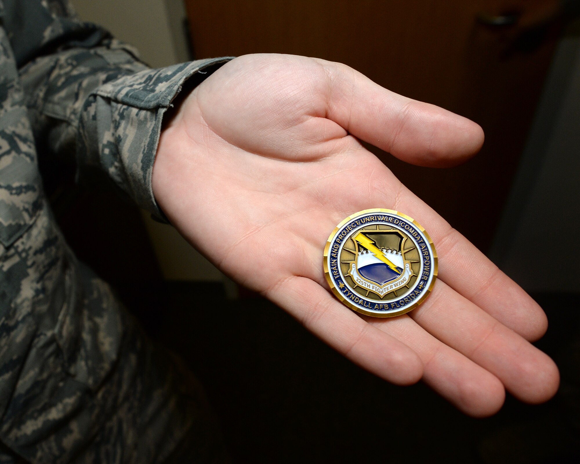 Senior Airman Larry D. Wildhaber, 325th Aerospace Medical Squadron public health specialist, displays a coin given to him by Col. Joseph D. Kunkel, 325th Fighter Wing vice commander. Public health specialists like Wildhaber ensure the medical readiness of deploying Airmen. (U.S. Air Force photo by Airman 1st Class Cody R. Miller/Released)