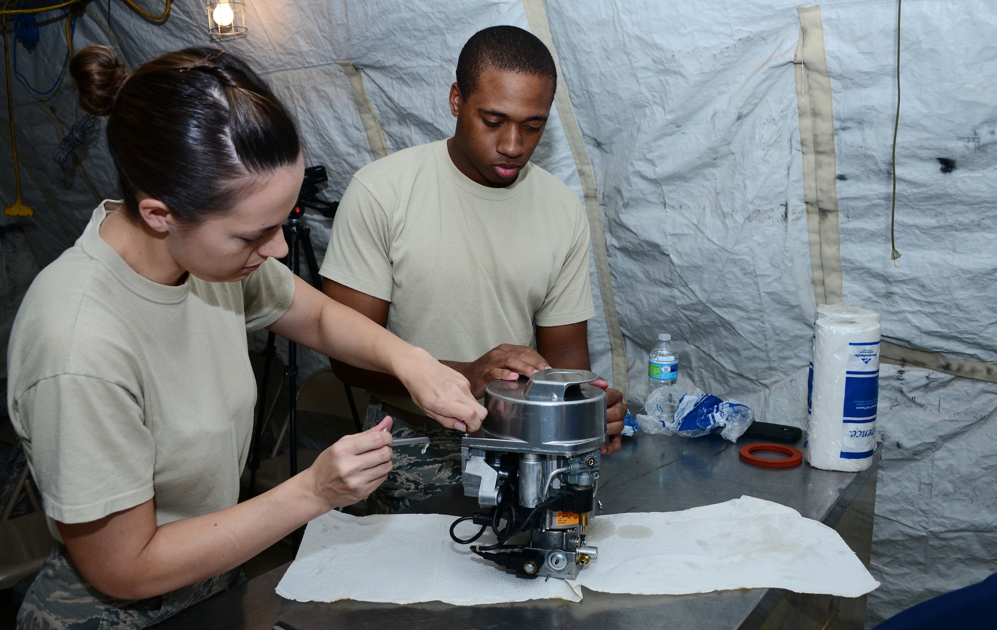 U.S. Air Force Staff Sgt. Ayala Angulo, 355th Force Support Squadron unit deployment manager, and 2nd Lt. Allante Staten, 355th FSS officer in charge of readiness, fix a Babington Airtronic burner during an expeditionary kitchen training at Davis-Monthan Air Force Base, Ariz., Sept. 30, 2015. The training was held at Desert Lighting City, D-M’s training ground that mirrors a deployed location.  (U.S. Air Force photo by Airman 1st Class Mya M. Crosby/Released)
