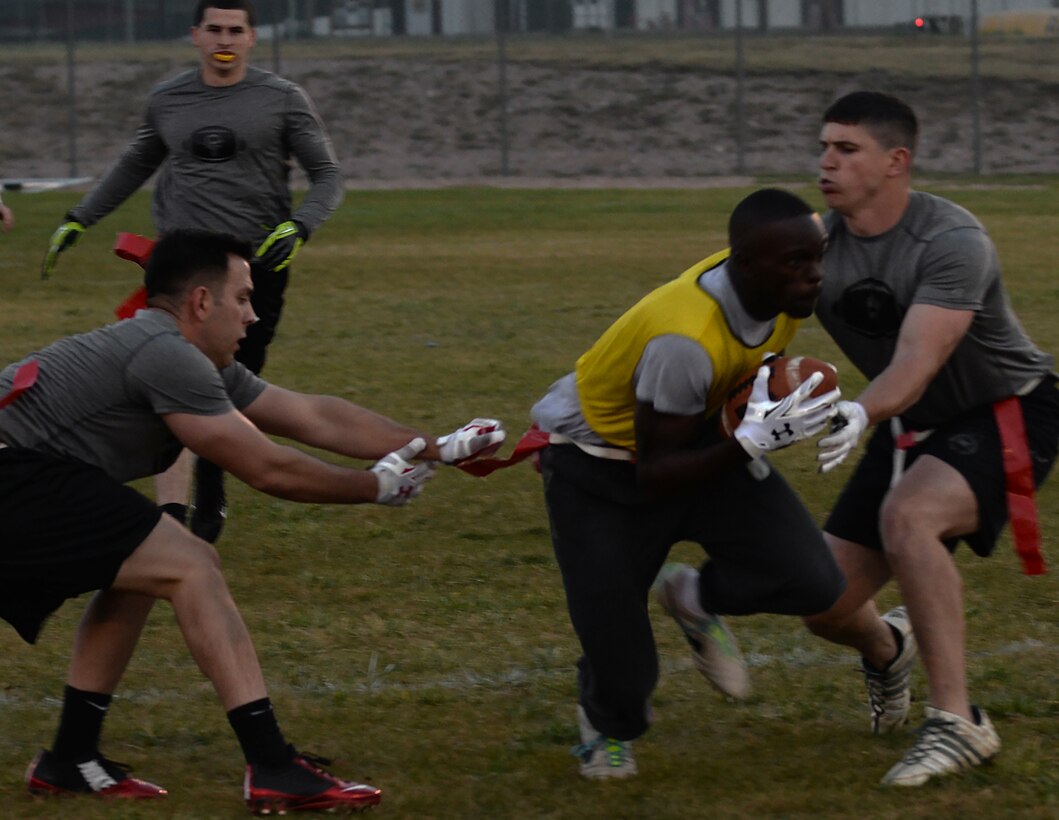 Travis Lawton, 790th Missile Security Forces Squadron, attempts to avoid two defenders from the Tactical Response Force team Oct. 5, 2015, during the 90th Missile Wing intermural flag football championship game on F.E. Warren Air Force Base, Wyo. (U.S. Air Force photo by Senior Airman Brandon Valle)