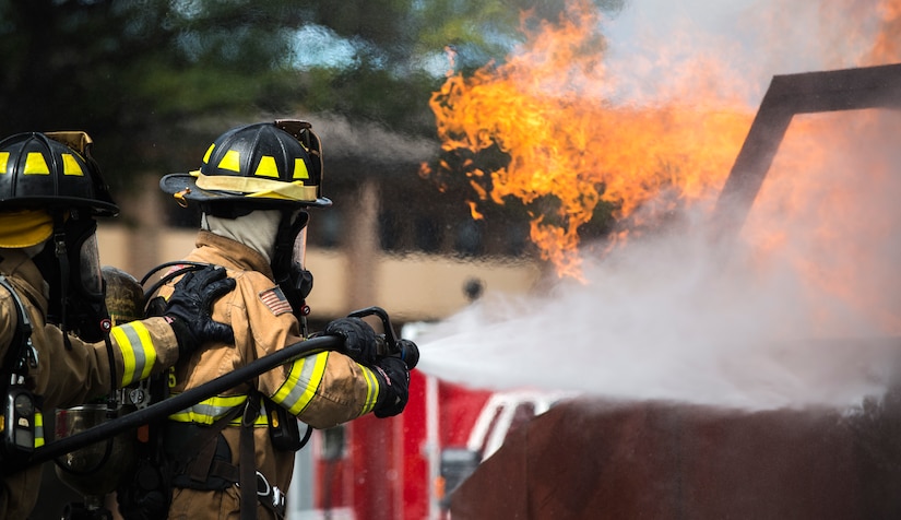 Airman 1st Class Austyn Helgeson and Senior Airman Scott Burdick, 11th Wing Civil Engineer firefighters, put out a fire during a live fire exercise at Joint Base Andrews, Md., Oct. 7, 2015. The exercise was part of the fire prevention week on JBA. (U.S Air Force photo by Airman 1st Class Philip Bryant/Released)