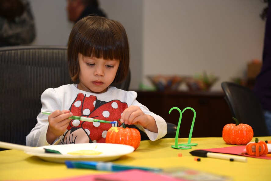 A young girl of a deployed McChord member, paints a pumpkin during the deployed family dinner at the Chapel Support Center on Joint Base Lewis-McChord, Wash., Oct. 2, 2015. More than 250 people attended the event. (U.S. Air Force photos/Senior Airman Naomi Griego) 