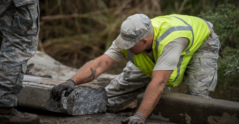 Staff Sgt. Devin Kennedy, 628th Civil Engineer Squadron heavy equipment operator, pulls a concrete slab to its designated position Oct. 6, 2015, on a road on Joint Base Charleston – Weapons Station, S.C. While hurricane Joaquin did not make landfall on the east coast, a constant flow of heavy rain caused flooding throughout the Carolinas. The 628th CES quickly accessed the damage and took action to fix and restore base assets. (U.S. Air Force photo/Airman 1st Class Clayton Cupit)