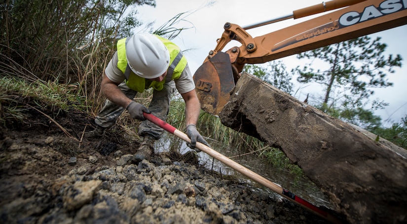 Staff Sgt. Devin Kennedy, 628th Civil Engineer Squadron heavy equipment operator, makes room for a sewer cover to be placed Oct. 6, 2015, on a road on Joint Base Charleston – Weapons Station, S.C. While hurricane Joaquin did not make landfall on the east coast, a constant flow of heavy rain caused flooding throughout the Carolinas. The 628th CES quickly accessed the damage and took action to fix and restore base assets. (U.S. Air Force photo/Airman 1st Class Clayton Cupit)