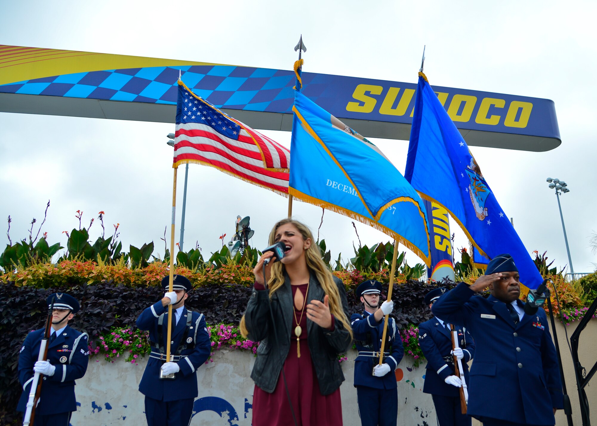 Payton Taylor sings the national anthem while 1st Lt. Kevin Pugh, 436th Airlift Wing chaplain, salutes and members of the Dover Air Force Base Honor Guard present the colors during the pre-race ceremonies of the 2015 Hisense 200 NASCAR Xfinity Series race Oct. 3, 2015, at the Dover International Speedway in Dover, Del. Airmen also volunteered at the USO Military Village and Monster Fun Zone showcasing a wide variety of Dover AFB’s mission related equipment. (U.S. Air Force photo/Senior Airman William Johnson)