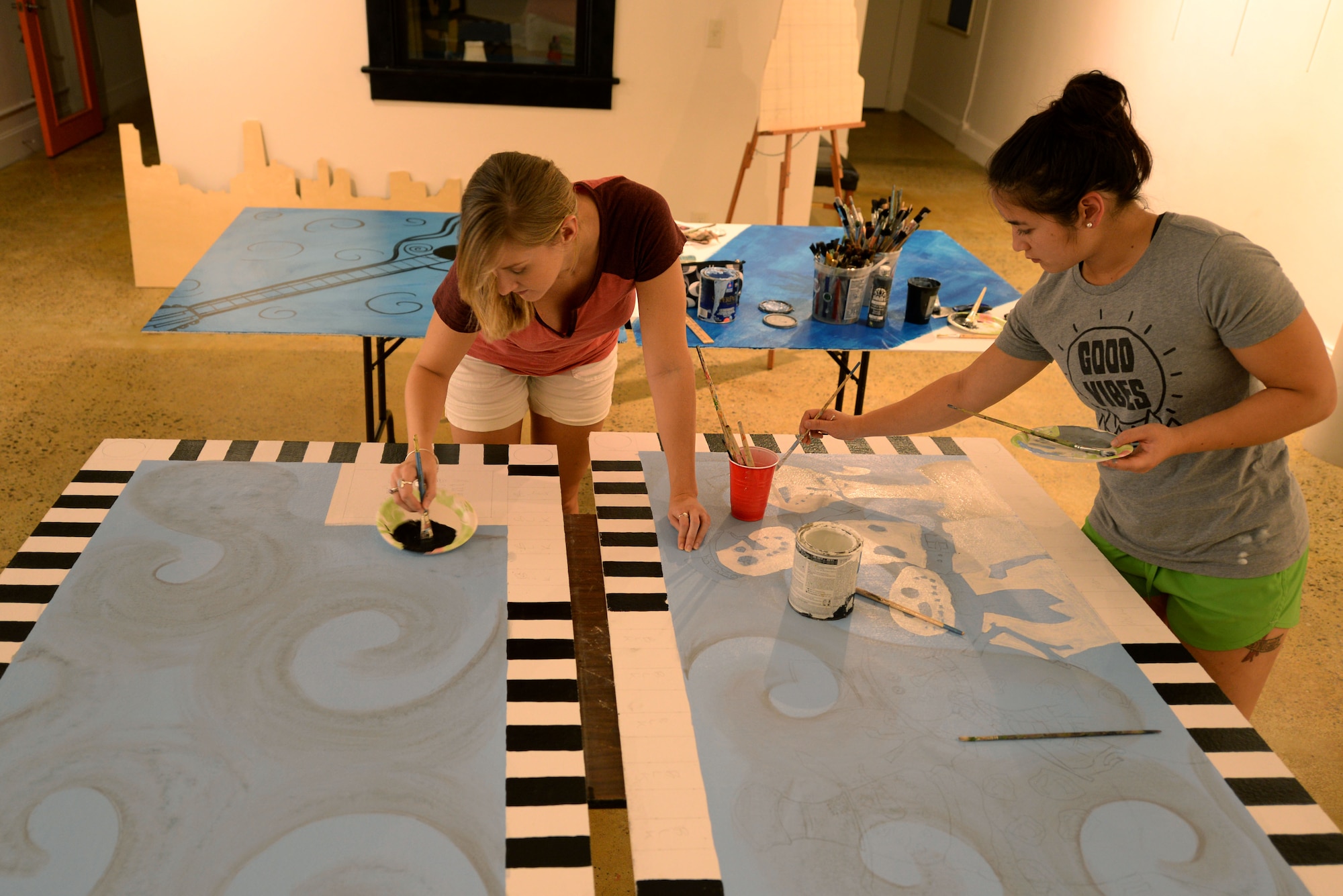 Heather Reynolds (left), gallery director at the Arts Council of Wayne County, and 1st Lt. Monica Hottle, Detachment 15 chief of education and training, work on paintings for two new art alleys, Sept. 21, 2015, at the Arts Council of Wayne County in downtown Goldsboro, North Carolina. The Arts Council tapped into the talent pool of the Seymour Johnson Air Force Base Painting Club to complete this project. (U.S. Air Force photo/Airman 1st Class Ashley Williamson)