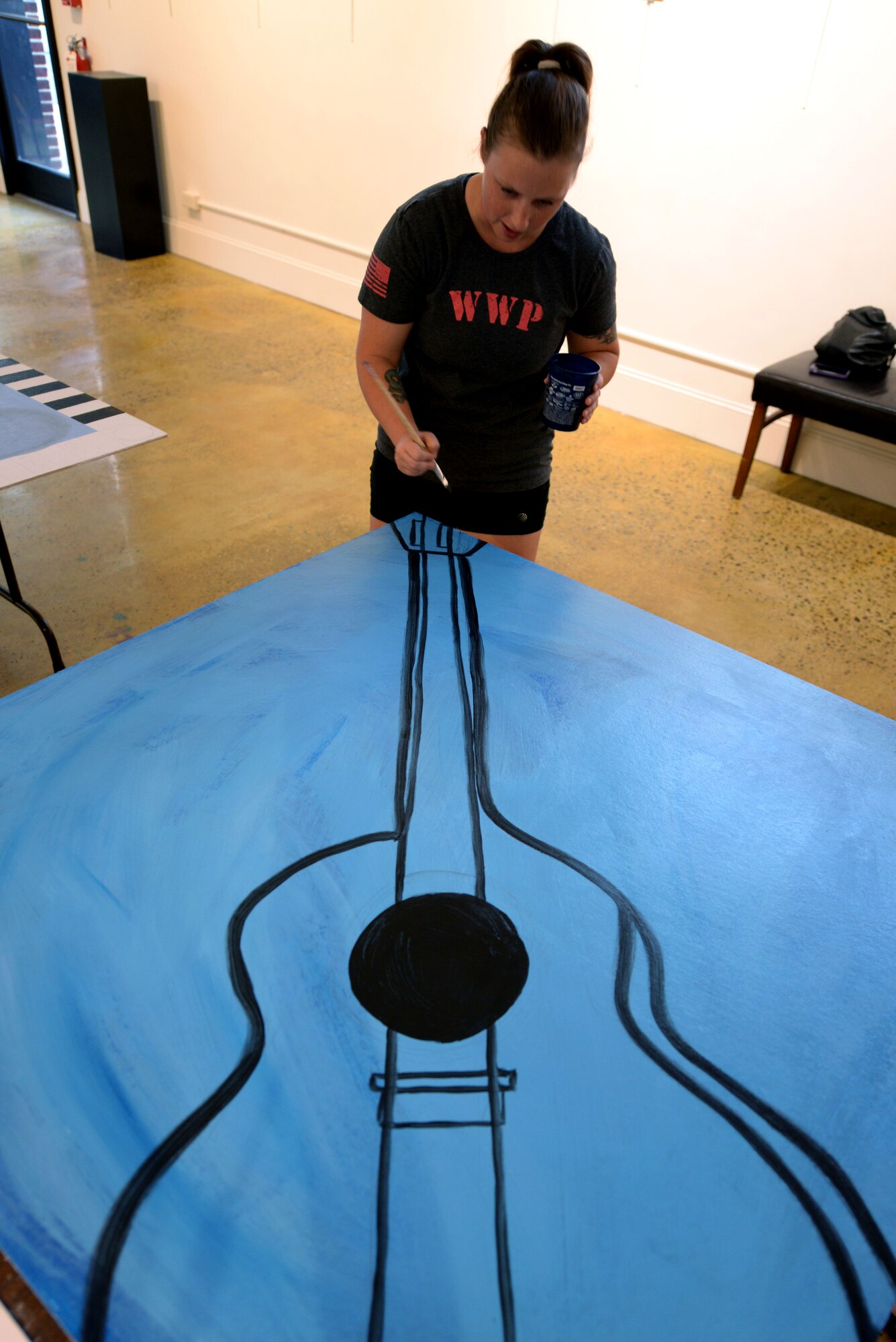 Staff Sgt. Tasha Stephenson, 372nd Training Squadron Detachment 2 aerospace ground equipment instructor, paints a guitar to hang in an art alley, Sept. 21, 2015, at the Arts Council of Wayne County in downtown Goldsboro, North Carolina. Stephenson and other members of the Seymour Johnson Air Force Base Painting Club contributed several paintings to two new art alleys in downtown Goldsboro, one music themed and the other travel themed. (U.S. Air Force photo/Airman 1st Class Ashley Williamson)