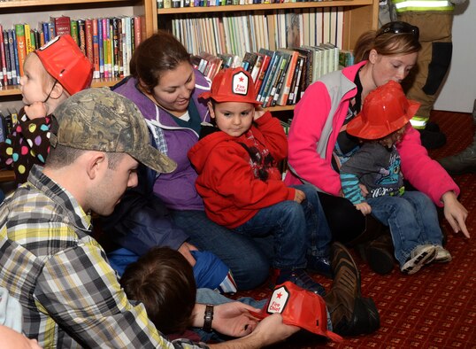 Families and friends gather to learn about Fire Prevention Week, Oct. 7, 2015, at the base library on RAF Mildenhall, England. Firefighters from the 100th Civil Engineer Squadron Fire Department read to the children with Sparky the Fire Dog and handed out souvenirs to encourage fire safety. The week’s events include a library reading, a fire department open house, bowling with Sparky and the annual fire muster.  (U.S. Air Force photo by Airman 1st Class Justine Rho/Released)  