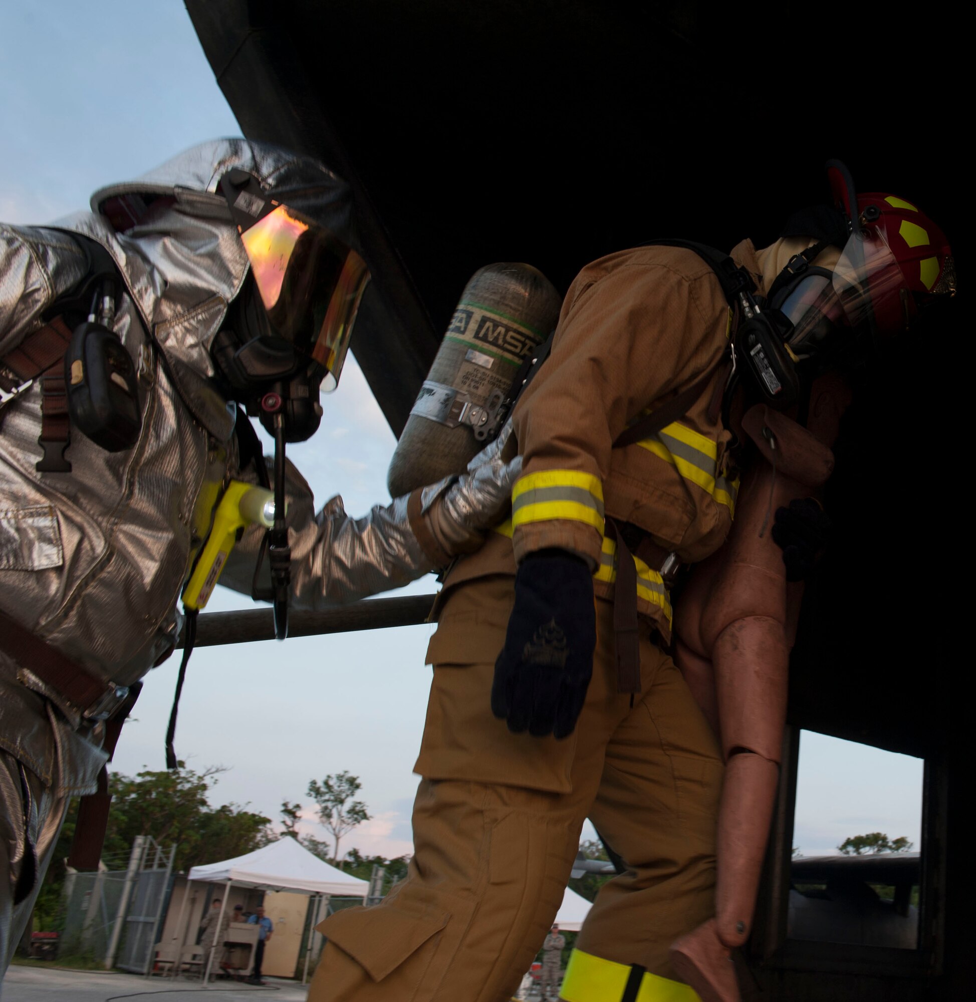 U.S. Air Force Col. James Laswell, 18th Medical Group commander, is led out of a Mobile Aircraft Fire Trainer by Staff Sgt. Nicholas Hayes, 18th Civil Engineer Squadron crew chief, during a live fire demonstration Oct. 6, 2015, on Kadena Air Base, Japan. The MAFT is designed to simulate aircraft fires, which provides realistic fire and rescue training for Kadena’s firefighting personnel. (U.S. Air Force photo by Airman 1st Class Lynette M. Rolen)