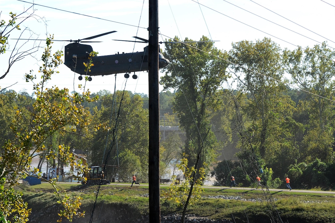 An Army CH-47 Chinook helicopter delivers an excavator to the Columbia Canal for the construction of a new dam during a statewide flood response caused by Hurricane Joaquin in Columbia, S.C., Oct. 6, 2015. South Carolina Air National Guard photo by Airman 1st Class Ashleigh S. Pavelek