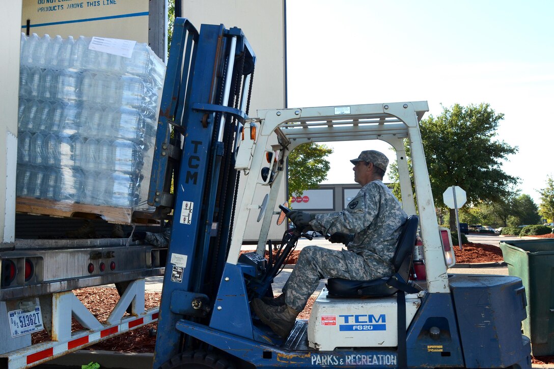 An Army National Guardsman operates a forklift to unload pallets of water for distribution to residents affected by heavy rainfall caused by Hurricane Joaquin at the Lower Richland High School, Columbia, S.C., Oct. 6, 2015. South Carolina Air National Guard photo by Airman 1st Class Ashleigh S. Pavelek  