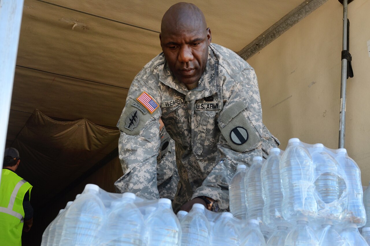 Army National Guardsman work with local law enforcement and volunteers to distribute drinking water to residents affected by heavy rainfall caused by Hurricane Joaquin at the Lower Richland High School, Columbia, S.C., Oct. 6, 2015. South Carolina Air National Guard photo by Airman 1st Class Ashleigh S. Pavelek 