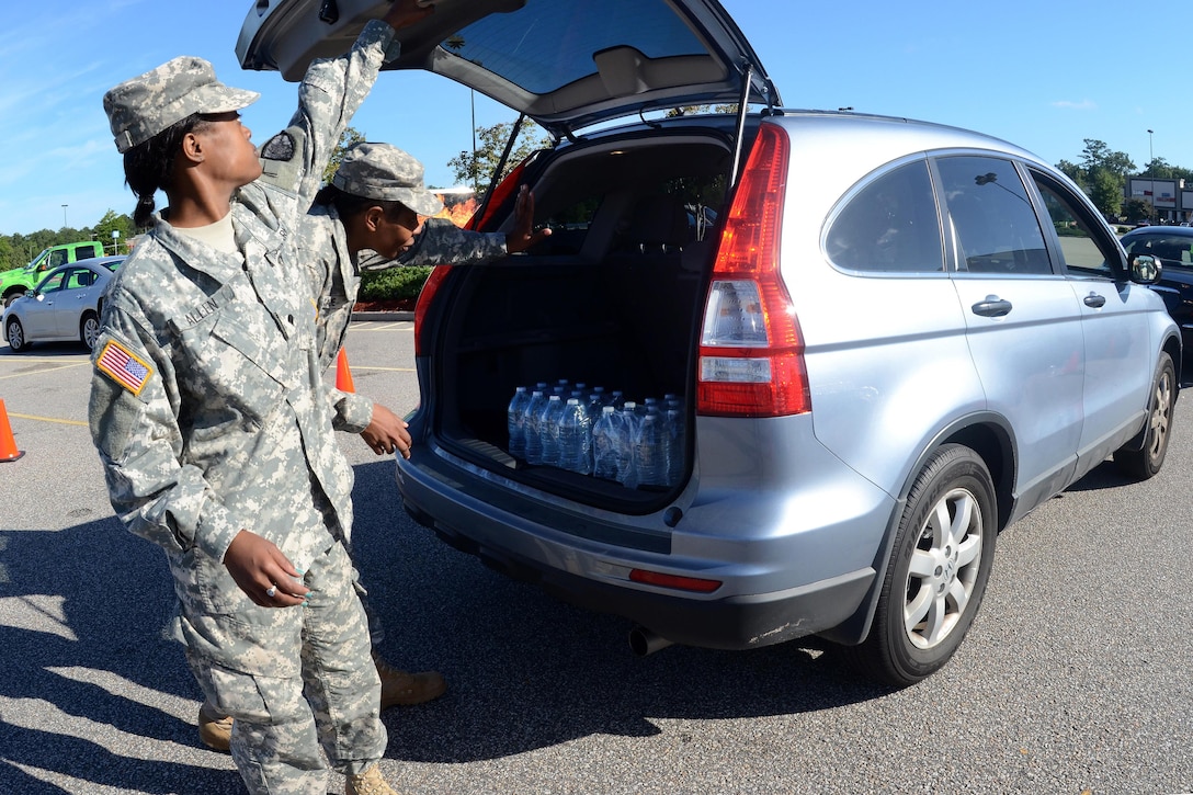 Army National Guardsman work with local law enforcement and volunteers to distribute drinking water to residents affected by heavy rainfall caused by Hurricane Joaquin at the Lower Richland High School, Columbia, S.C., Oct. 6, 2015. South Carolina Air National Guard photo by Airman 1st Class Ashleigh S. Pavelek 