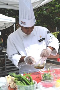 Spc. Nathanael J. Dewey, 103rd Sustainment Command (Expeditionary), mixes the seasoned dressing for the honey ginger salad with beef medallion served as the second course during the Military Culinary Competition held during the Barracks Row Fall Festival in Washington, Sept. 26, 2015. This is Dewey’s first year competing at this event. 