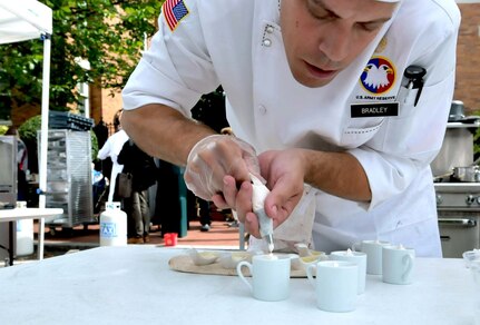 Staff Sgt. Orkie L. Bradley, 451st Sustainment Command (Expeditionary), puts the final touches on his white chocolate crème dessert, which accompanied macerated blueberries and crème brûlée as the fourth course of the meal that the Army Reserve Culinary Arts Team prepared at the Military Culinary Competition held during the Barracks Row Fall Festival in Washington, Sept. 26, 2015. Bradley is a second year competitor at this event. 