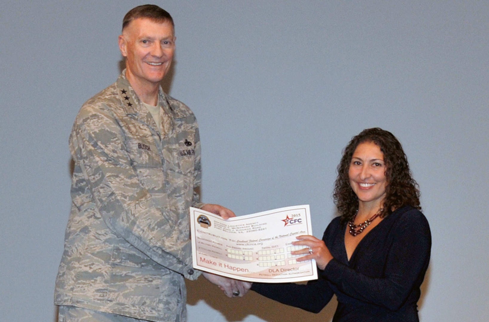 Defense Logistics Agency Director Air Force Lt. Gen. Andy Busch hands his Combined Federal Campaign pledge to DLA’s CFC Campaign Manager Emma Edmiston. The 2015 CFC kicked off Oct. 1 with a ceremony at the McNamara Headquarters Complex. 