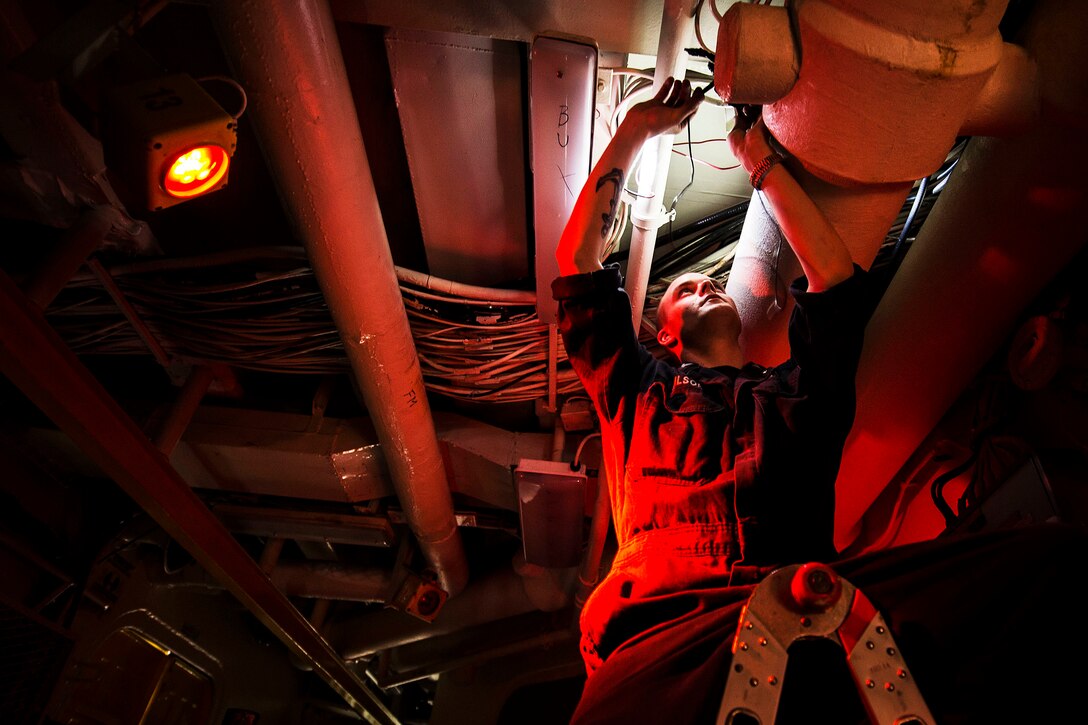 U.S. Navy Petty Officer 2nd Class Adam Wilson rewires a light fixture in a passageway aboard the USS Essex in the Arabian Gulf, Oct. 2, 2015. The Essex is supporting security efforts in the U.S. 5th Fleet area of responsibility. U.S. Navy photo by Petty Officer Class 2nd Class Huey D. Younger Jr.