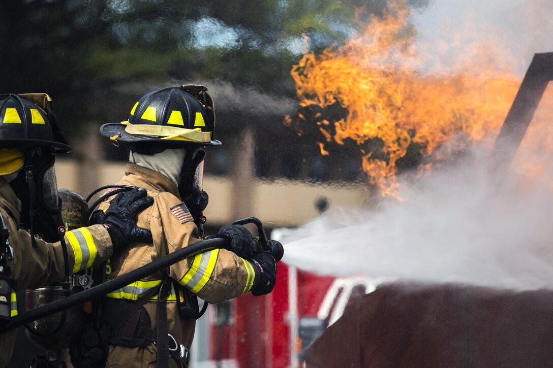Airman 1st Class Austyn Helgeson and Senior Airman Scott Burdick extinguish a fire during an exercise as part of the fire prevention week on Joint Base Andrews, Md., Oct. 7, 2015. Helgeson and Burdick are firefighters with the 11th Wing. U.S. Air Force photo by Airman 1st Class Philip Bryant