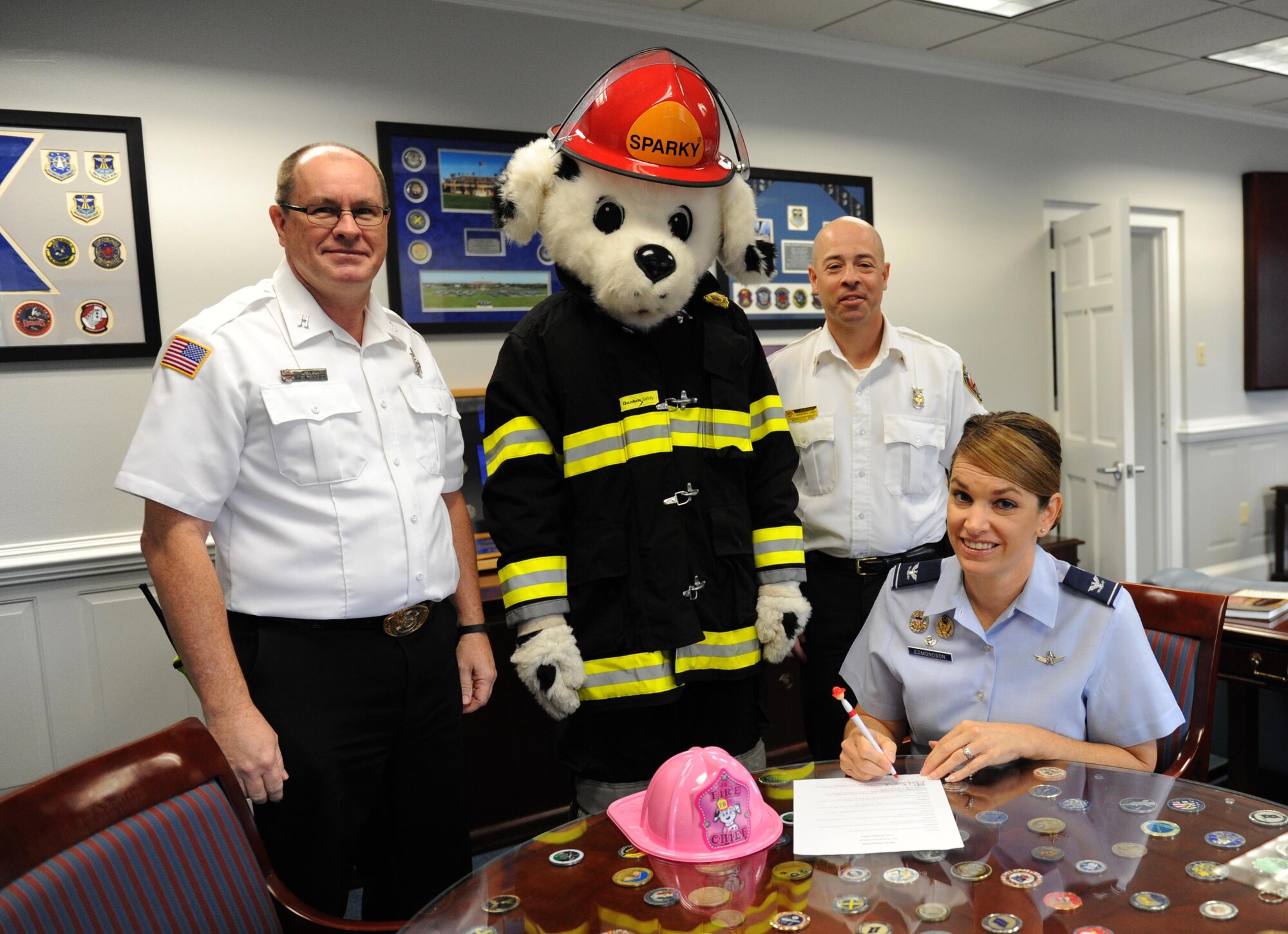 Col. Michele Edmondson, 81st Training Wing commander, signs the Fire Prevention Week Declaration as James Shirah, 81st Infrastructure Division fire inspector, Jason Sanders, 81st ID assistant chief of fire prevention, and Sparky the Fire Dog, stand behind her at the 81st Training Wing headquarters building, Oct. 5, 2015, Keesler Air Force, Miss. The week-long event includes fire drills, literature hand-outs and stove fire demonstrations around the base and concludes with an open house at the fire department Oct. 10. (U.S. Air Force photo by Kemberly Groue)