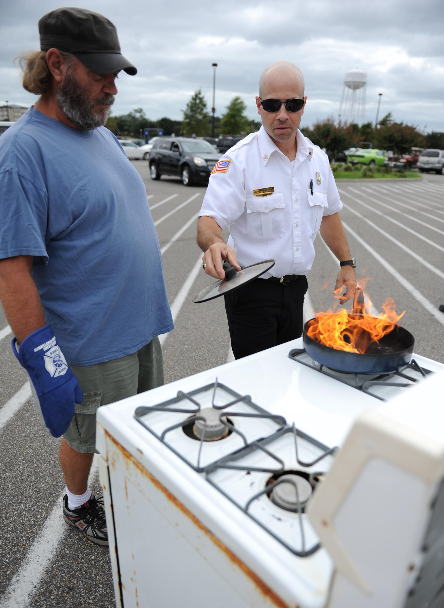 Retired U.S. Air Force Master Sgt. Ed Carmen watches as Jason Sanders, 81st Infrastructure Division assistant chief of fire prevention, demonstrates how to safely put out a stove fire during Fire Prevention Week outside of the Base Exchange, Oct. 5, 2015, Keesler Air Force Base, Miss. The week-long event includes fire drills, literature hand-outs and stove fire demonstrations around the base and concludes with an open house at the fire department Oct. 10. (U.S. Air Force photo by Kemberly Groue)