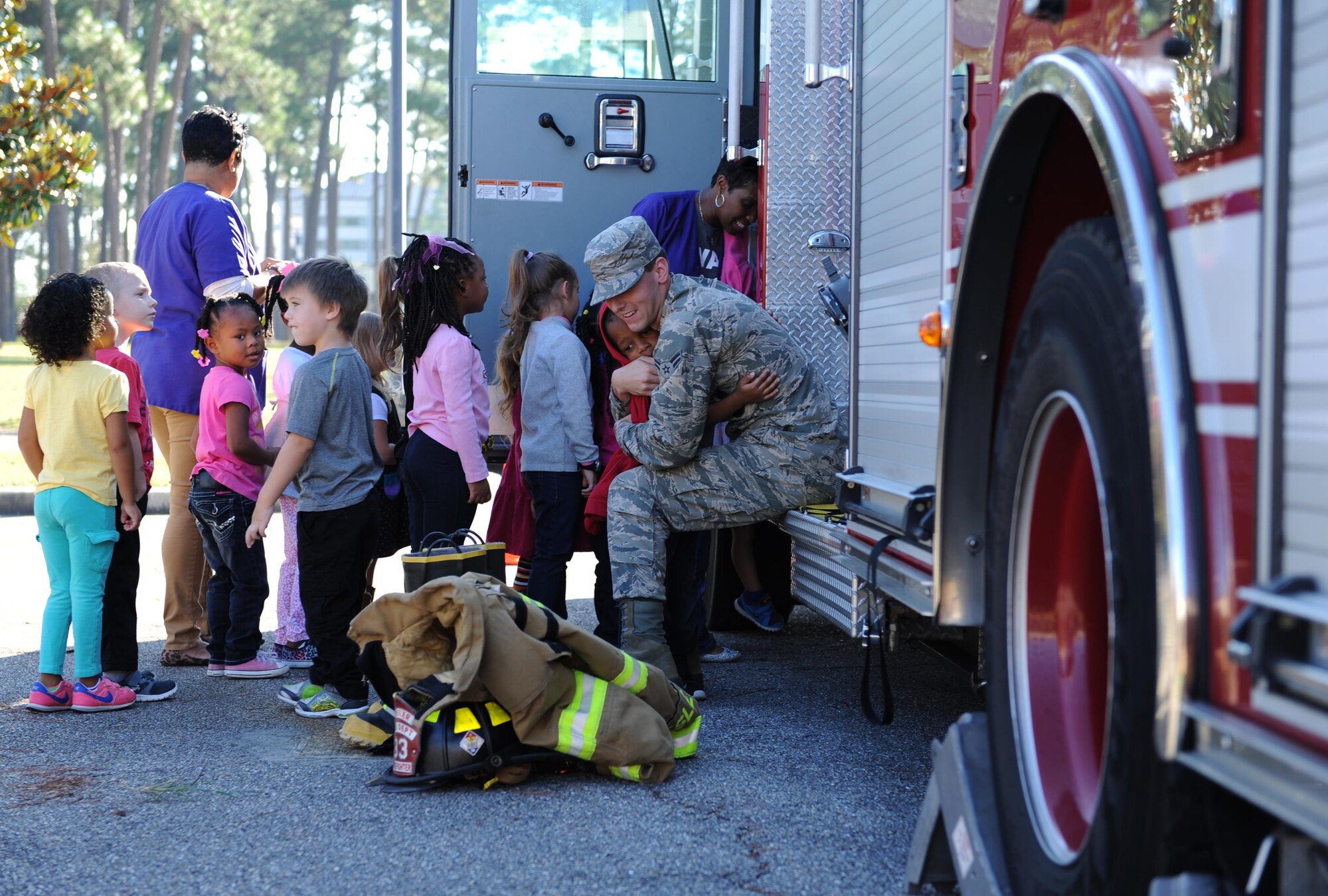 Airman 1st Class Erik McAskill, 81st Infrastructure Division firefighter driver operator, receives hugs from children at the child development center during a Fire Prevention Week visit, Oct. 6, 2015, Keesler Air Force Base, Miss.  Throughout the week the Keesler Fire Department is conducting random fire drills, touring various facilities with Sparky the Fire Dog, passing out fire safety handouts and fire hats for children and providing stove and fire extinguisher demonstrations. The week–long event will conclude with an open house at the fire station 10 a.m. to 2 p.m. Oct. 10.