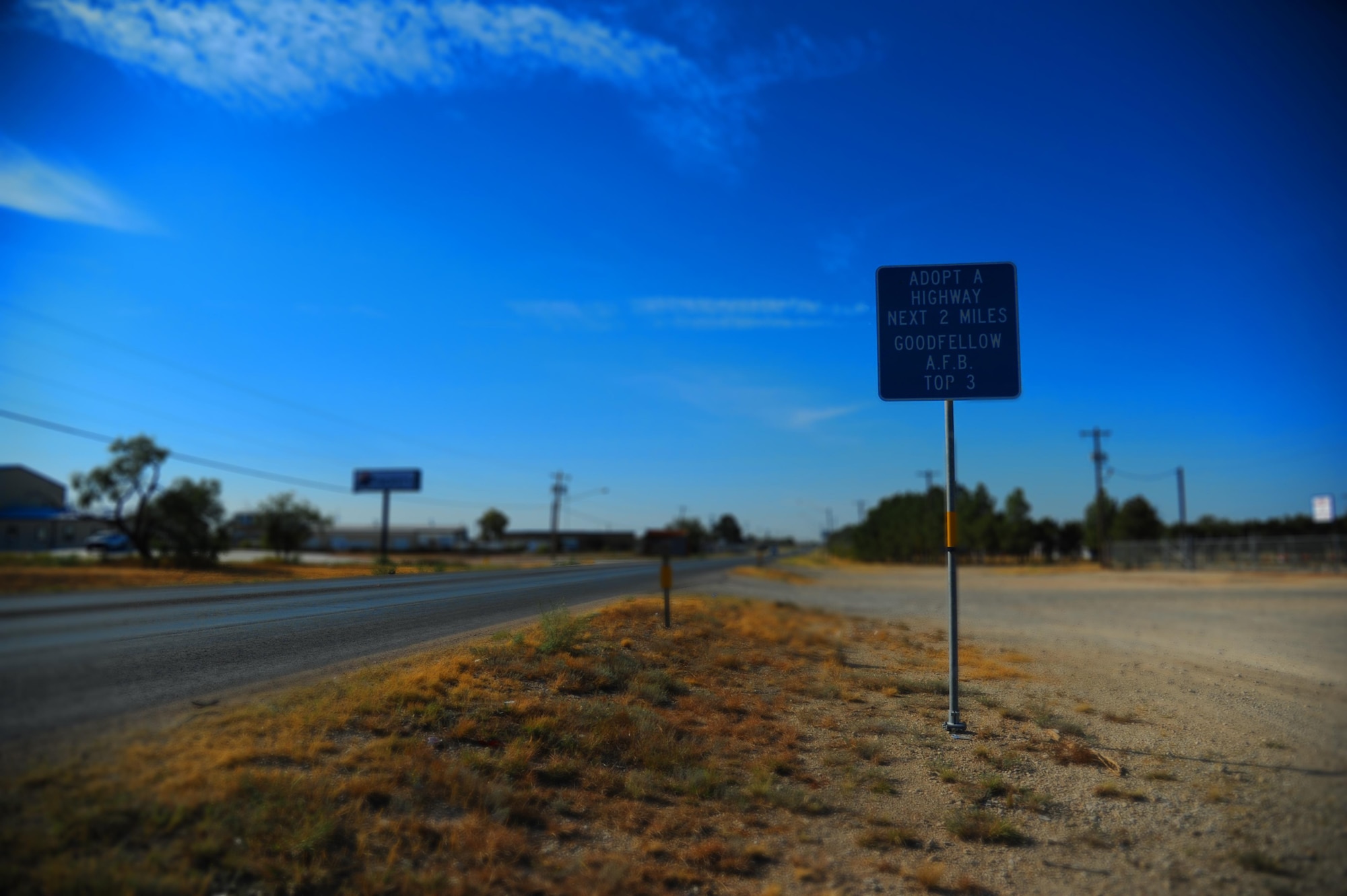 An Adopt-a-Highway sign sits on Christoval Road, a road in San Angelo, Texas, that the Goodfellow Air Force Base Top 3 organization has adopted. Goodfellow has kept the San Angelo community clean by adopting highways since 2007. (U.S. Air Force illustration by Airman Caelynn Ferguson/Released)