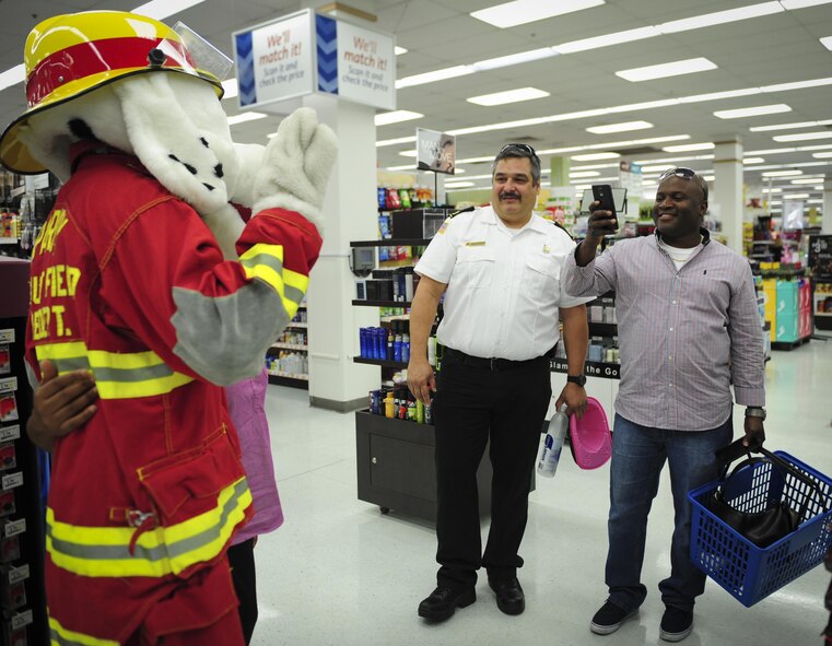 Shoppers at the Base Exchange take a photo with Sparky the Fire Dog, National Fire Prevention Association spokesdog, during Fire Prevention Week on Hurlburt Field, Fla., Oct. 4, 2015. Sparky the Fire Dog and Airmen with the Hurlburt Field Fire Department greet Airmen on base, visited Child Development Centers, the base library and other locations around base throughout the week to educate and raise awareness about fire prevention. This year’s theme is “Hear the BEEP, where you SLEEP: Every Bedroom Needs A Working Smoke Alarm!” Fire Prevention Week will conclude with a fire muster challenge open to Airmen around base, Oct. 9. (U.S. Air Force photo by Senior Airman Meagan Schutter)