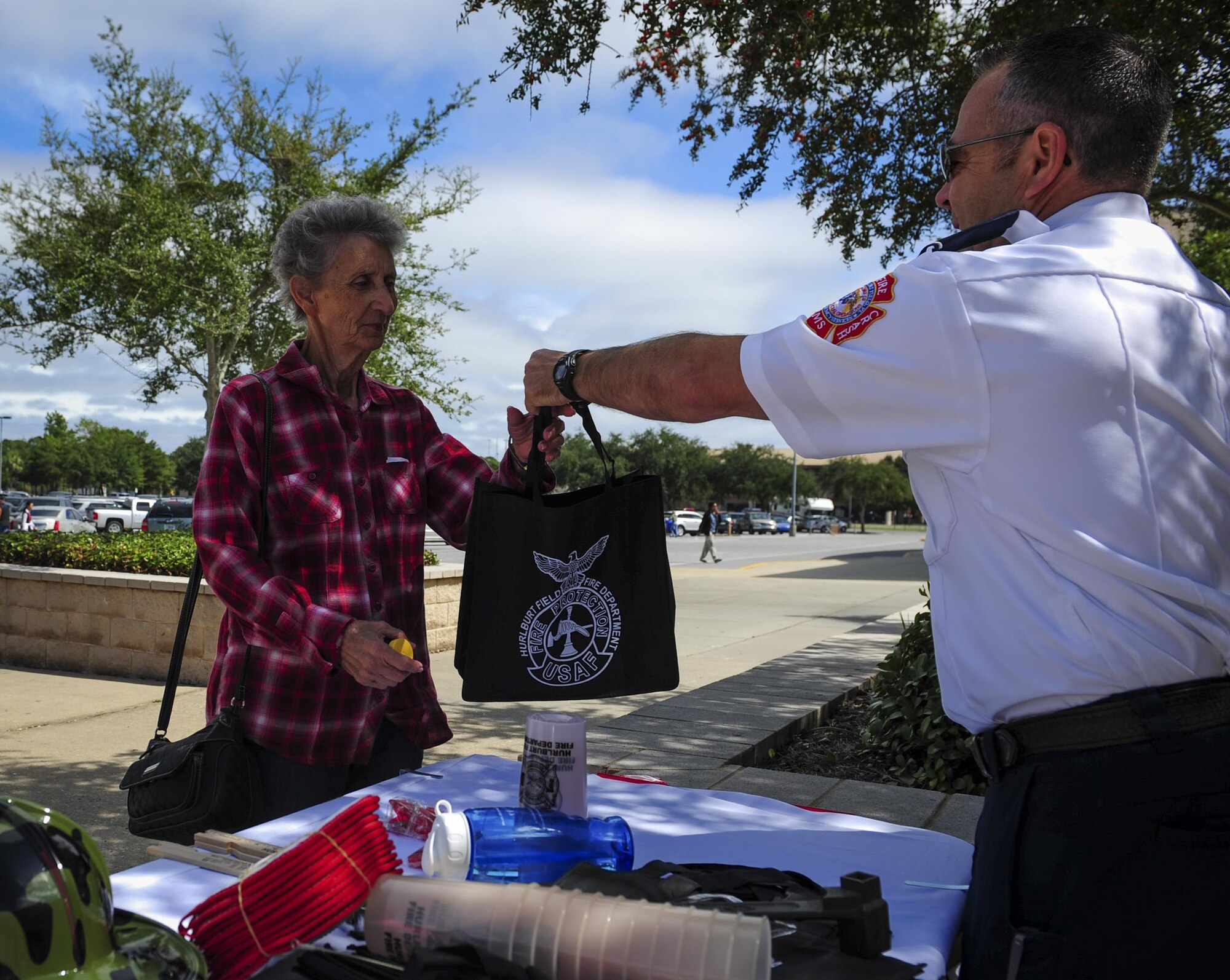 Favies Hill, 1st Special Operations Civil Engineer Squadron fire inspector, hands out a fire department gift bag at the Base Exchange during Fire Prevention Week on Hurlburt Field, Fla., Oct. 4, 2015. Sparky the Fire Dog and Airmen with the Hurlburt Field Fire Department greet Airmen on base, visited Child Development Centers, the base library and other locations around base throughout the week to educate and raise awareness about fire prevention. This year’s theme is “Hear the BEEP, where you SLEEP: Every Bedroom Needs A Working Smoke Alarm!” Fire Prevention Week will conclude with a fire muster challenge open to Airmen around base, Oct. 9. (U.S. Air Force photo by Senior Airman Meagan Schutter)