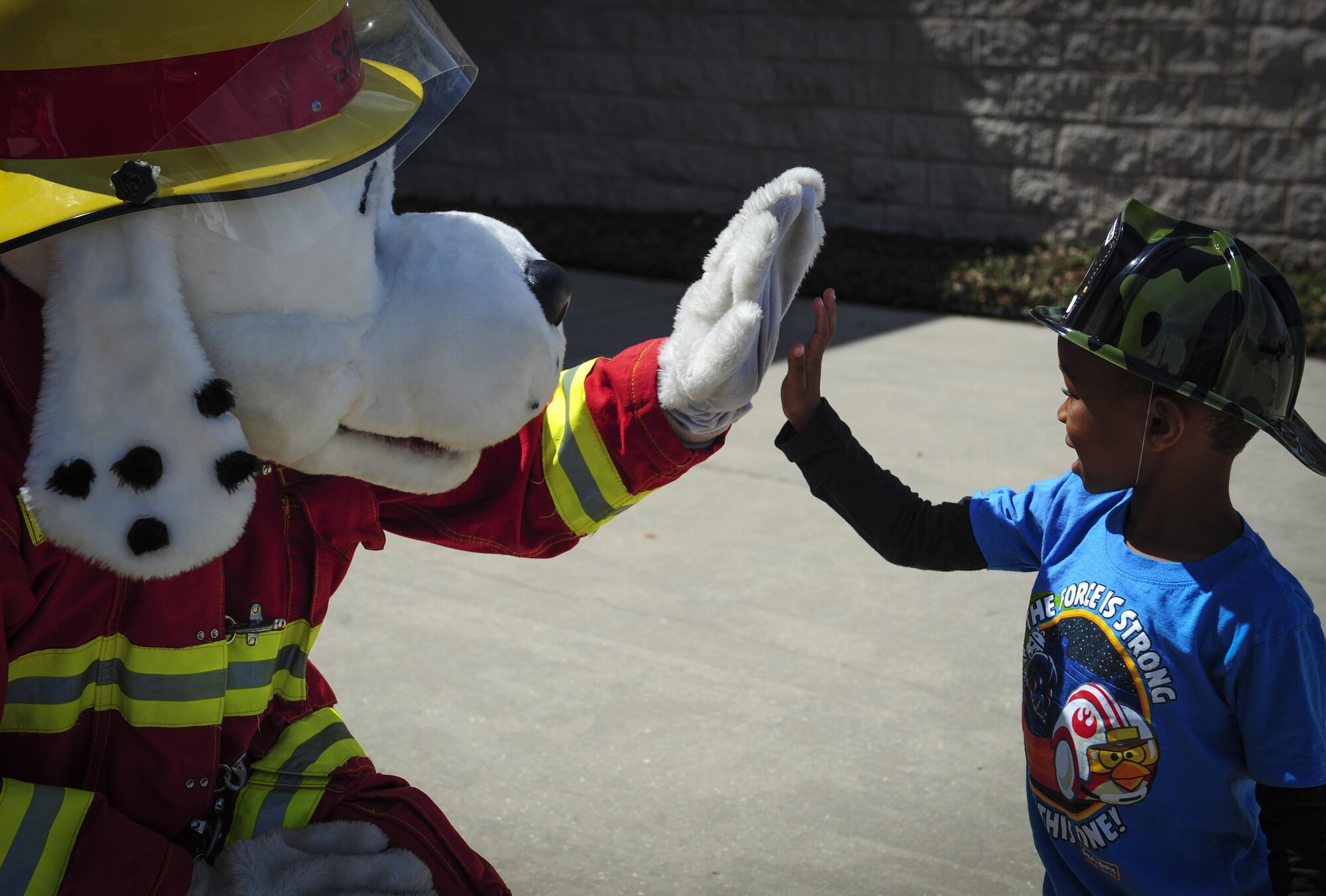 Sparky the Fire Dog, National Fire Prevention Association spokesdog, gives a high five to a child outside the Base Exchange during Fire Prevention Week on Hurlburt Field, Fla., Oct. 4, 2015. Sparky the Fire Dog, National Fire Prevention Association spokesdog, gives a high five to a child outside the Base Exchange during Fire Prevention Week on Hurlburt Field, Fla., Oct. 4, 2015. Sparky the Fire Dog and Airmen with the Hurlburt Field Fire Department greet Airmen on base, visited Child Development Centers, the base library and other locations around base throughout the week to educate and raise awareness about fire prevention. This year’s theme is “Hear the BEEP, where you SLEEP: Every Bedroom Needs A Working Smoke Alarm!” Fire Prevention Week will conclude with a fire muster challenge open to Airmen around base, Oct. 9. (U.S. Air Force photo by Senior Airman Meagan Schutter)