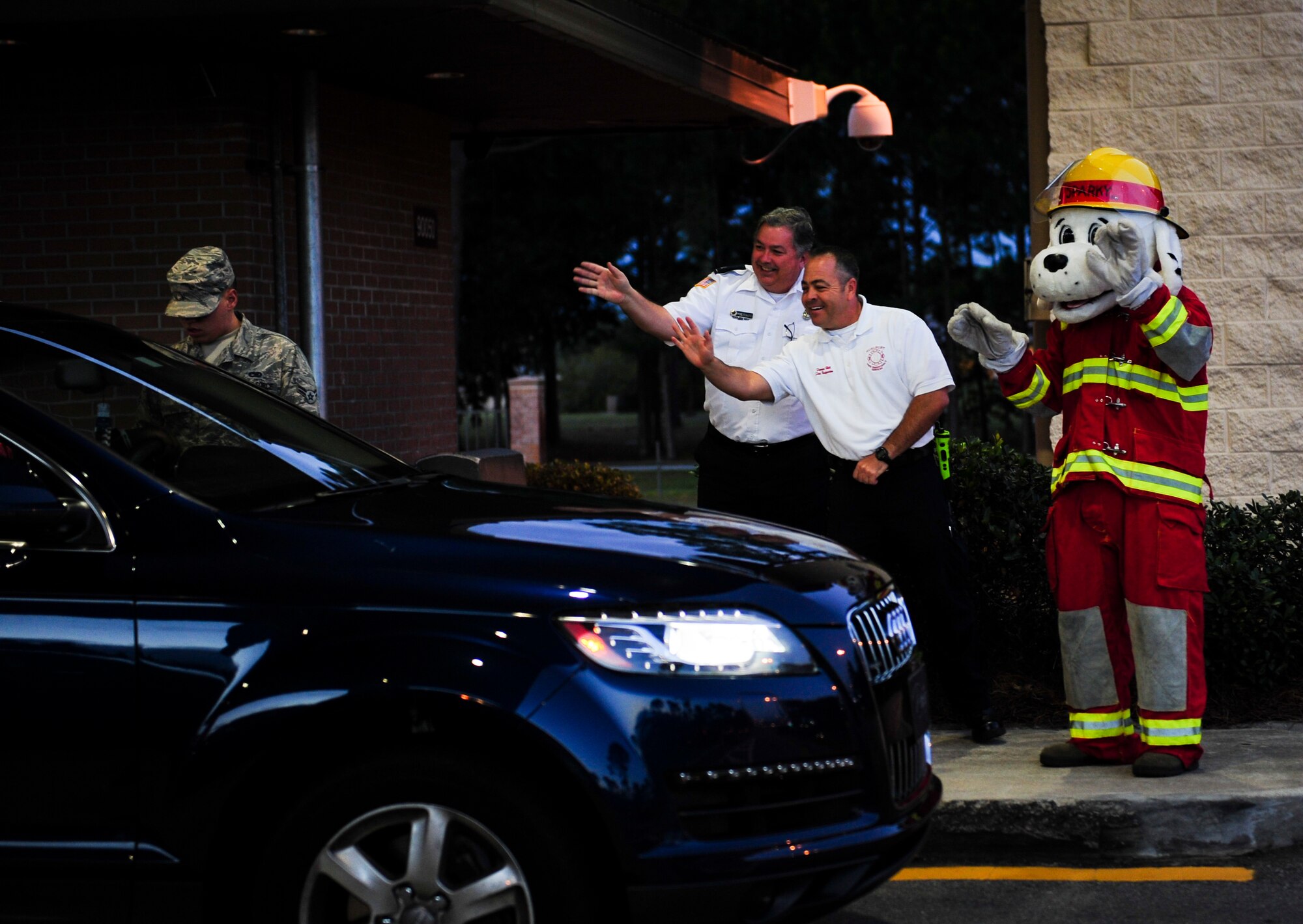 Sparky the Fire Dog, National Fire Prevention Association spokesdog, Favies Hill, and Fred Richardson, 1st Special Operations Civil Engineer Squadron fire inspectors, wave to Airmen entering base during Fire Prevention Week on Hurlburt Field, Fla., Oct. 5, 2015.Sparky the Fire Dog and Airmen with the Hurlburt Field Fire Department greet Airmen on base, visited Child Development Centers, the base library and other locations around base throughout the week to educate and raise awareness about fire prevention. This year’s theme is “Hear the BEEP, where you SLEEP: Every Bedroom Needs A Working Smoke Alarm!” Fire Prevention Week will conclude with a fire muster challenge open to Airmen around base, Oct. 9. (U.S. Air Force photo by Senior Airman Meagan Schutter)