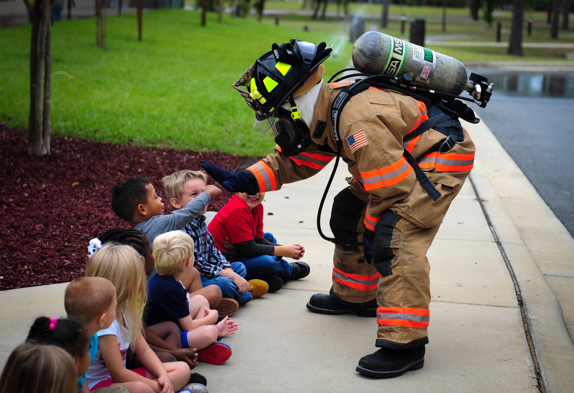 Airman 1st Class Josh Carrico, 1st Special Operations Civil Engineer Squadron firefighter, gives children  high-fives at the Child Development Center during Fire Prevention Week on Hurlburt Field, Fla., Oct. 5, 2015. Sparky the Fire Dog and Airmen with the Hurlburt Field Fire Department greet Airmen on base, visited Child Development Centers, the base library and other locations around base throughout the week to educate and raise awareness about fire prevention. This year’s theme is “Hear the BEEP, where you SLEEP: Every Bedroom Needs A Working Smoke Alarm!” Fire Prevention Week will conclude with a fire muster challenge open to Airmen around base, Oct. 9. (U.S. Air Force photo by Senior Airman Meagan Schutter)