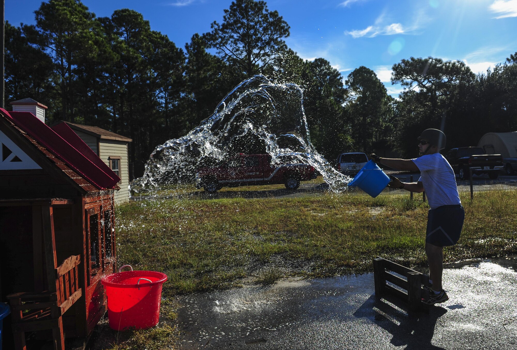 An Airman with the 823rd Red Horse Squadron tosses water on a toy house during a fire muster challenge on Hurlburt Field, Fla., Oct. 8, 2015. Sparky the Fire Dog, National Fire Prevention Association spokesdog, and Airmen with the Hurlburt Field Fire Department welcomed Airmen on base, visited Child Development Centers, the base library and other locations around base throughout the week to educate and raise awareness about fire prevention. This year’s theme is “Hear the BEEP, where you SLEEP: Every Bedroom Needs A Working Smoke Alarm!” Fire Prevention Week concluded with a fire muster challenge that was open to Hurlburt Airmen. (U.S. Air Force photo by Senior Airman Meagan Schutter)