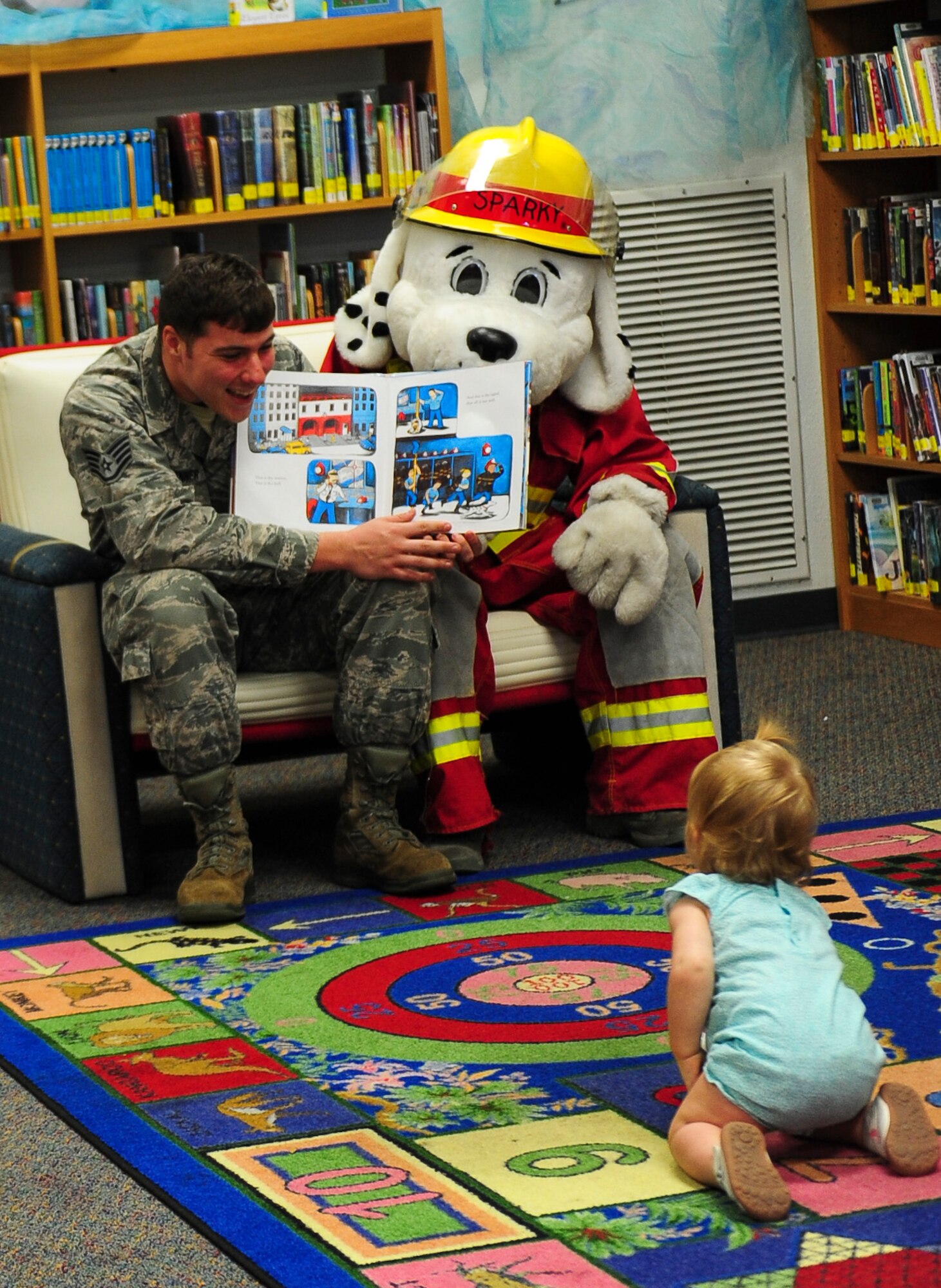 Christopher Benner, 1st Special Operations Squadron Civil Engineer Squadron firefighter, reads to a child at the library during Fire Prevention Week on Hurlburt Field, Fla., Oct. 8, 2015. Sparky the Fire Dog, National Fire Prevention Association spokesdog, and Airmen with the Hurlburt Field Fire Department welcomed Airmen on base, visited Child Development Centers, the base library and other locations around base throughout the week to educate and raise awareness about fire prevention. This year’s theme is “Hear the BEEP, where you SLEEP: Every Bedroom Needs A Working Smoke Alarm!” Fire Prevention Week concluded with a fire muster challenge that was open to Hurlburt Airmen. (U.S. Air Force photo by Senior Airman Meagan Schutter)