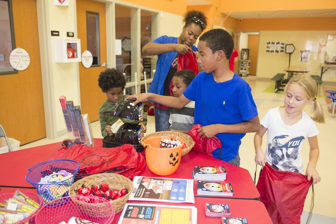 Brandi Silva, Child Care Program Assistant aboard Marine Corps Logistics Base Barstow Youth Activites Center, oversees Dominic Singleton, age 6, Chance Little, age 5, Dammian Singleton age 9, and Kayla Pettis, age 7, collect several keepsakes from the fire safety table at Youth Activites Center, Oct 8.