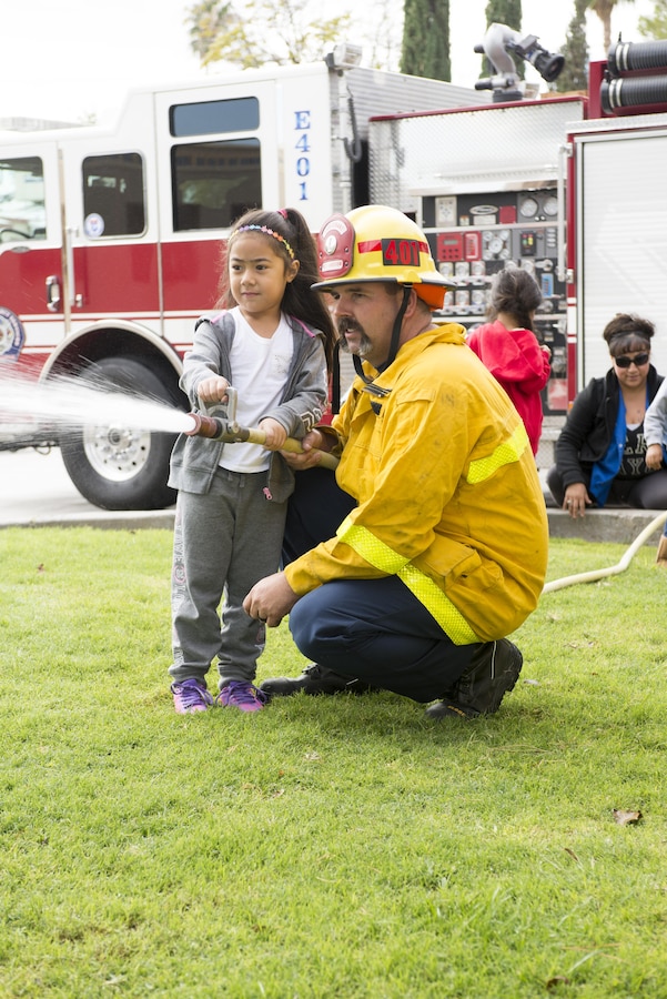 Children learn about fire safety and equipment during the annual Fire Prevention Week events with firefighters and paramedics at Marine Corps Fire Department aboard Marine Corps Logistics Base Barstow, Calif., Oct. 6. Joe Haresky, fire lieutenant aboard MCLB Barstow, demonstrates the proper method of using a fire hose to children from the Child Development Center aboard MCLB Barstow.