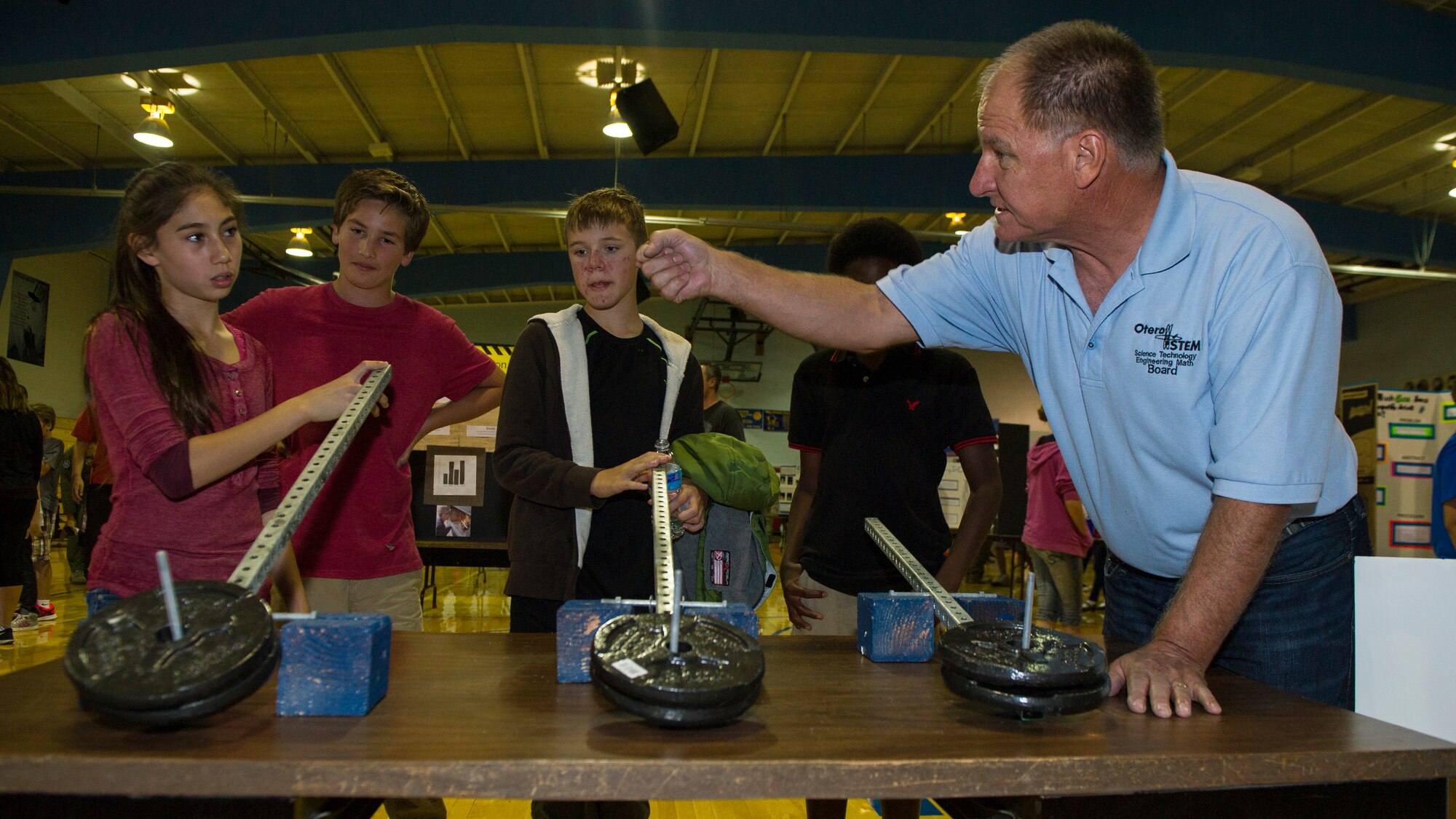 Frederick Stong, the president of Otero Science Technology Engineering and Math, teaches students from Holloman Middle School about weight distribution during the Holloman Middle School Science Fair, Oct. 7. Each plate weighed the same, but, because of the difference in weight distribution, the weights did not feel equally heavy. The gym was filled with students’ science experiments, as well as presentations from various organizations at Holloman Air Force Base and throughout the city of Alamogordo. (U.S. Air Force photo by Airman 1st Class Emily A. Kenney)    