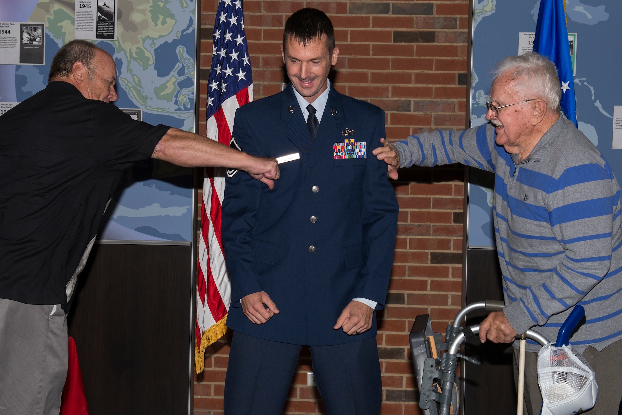 Master Sgt. Michael Tucker, Cyber Space Support Squadron NCOIC of Cyber Operation Requirements, has his Master Sgt. stripes tacked on by his father, Robert Tucker II and his grandfather, Robert Tucker Sr. Michael Tucker attributes both his father and grandfather for many of his successes in his career. (U.S. Air Force Photo by Senior Airman Megan Friedl)