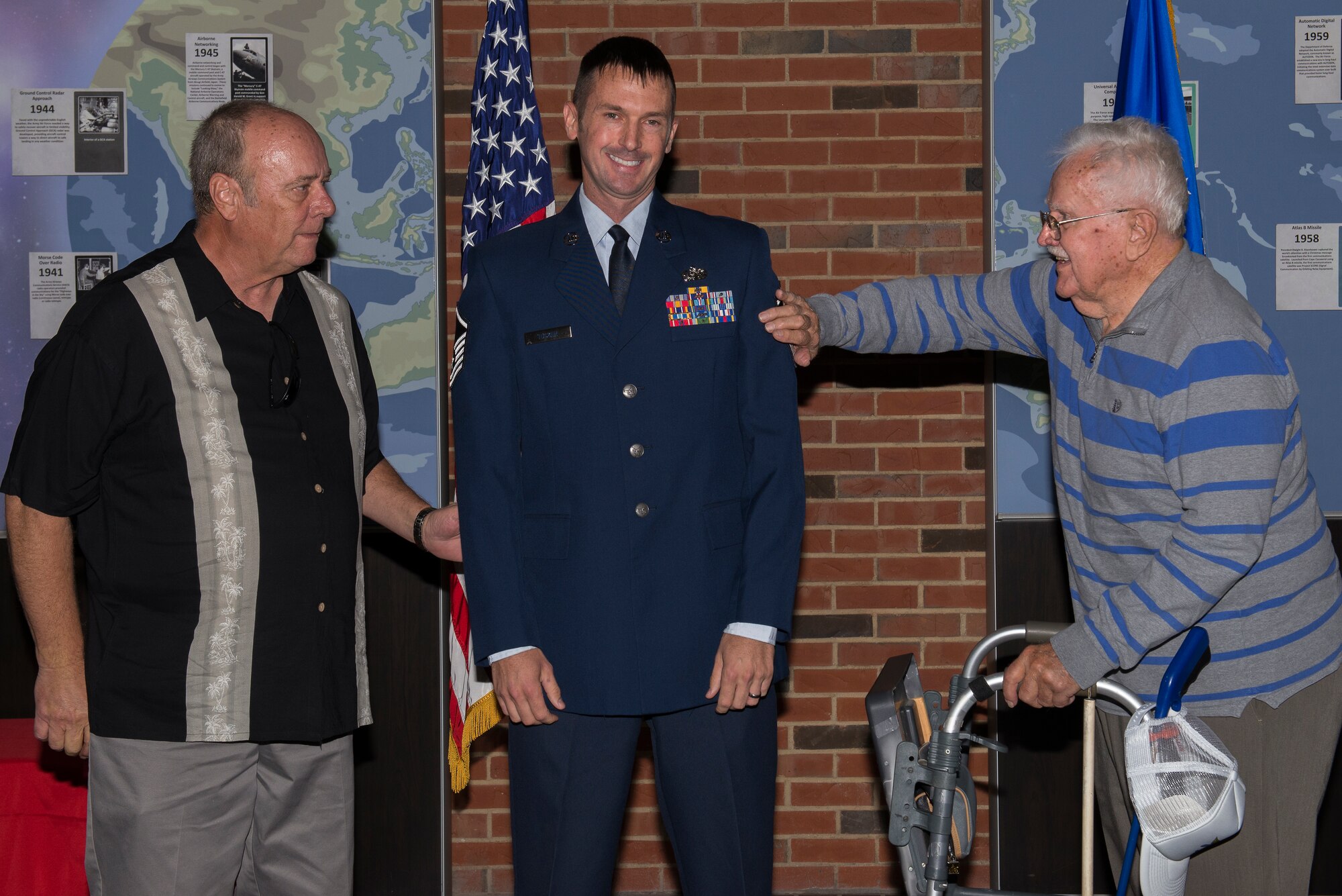 Master Sgt. Michael Tucker, Cyber Space Support Squadron NCOIC of Cyber Operation Requirements, has his Master Sgt. stripes tacked on by his father, Robert Tucker II and his grandfather, Robert Tucker Sr. Michael Tucker attributes both his father and grandfather for many of his successes in his career. (U.S. Air Force Photo by Senior Airman Megan Friedl)