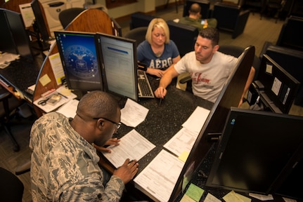 Airman Christopher Tillman, 628th Comptroller Squadron financial systems technician, helps SSgt. Rob MacPeek, 628th Logistics Readiness Squadron vehicle maintenance operator and Candace MacPeek file paperwork in the finance office on Joint Base Charleston – Air Base, S.C., Oct. 7, 2015. MacPeek and his wife, Candace, were updating their marital status.