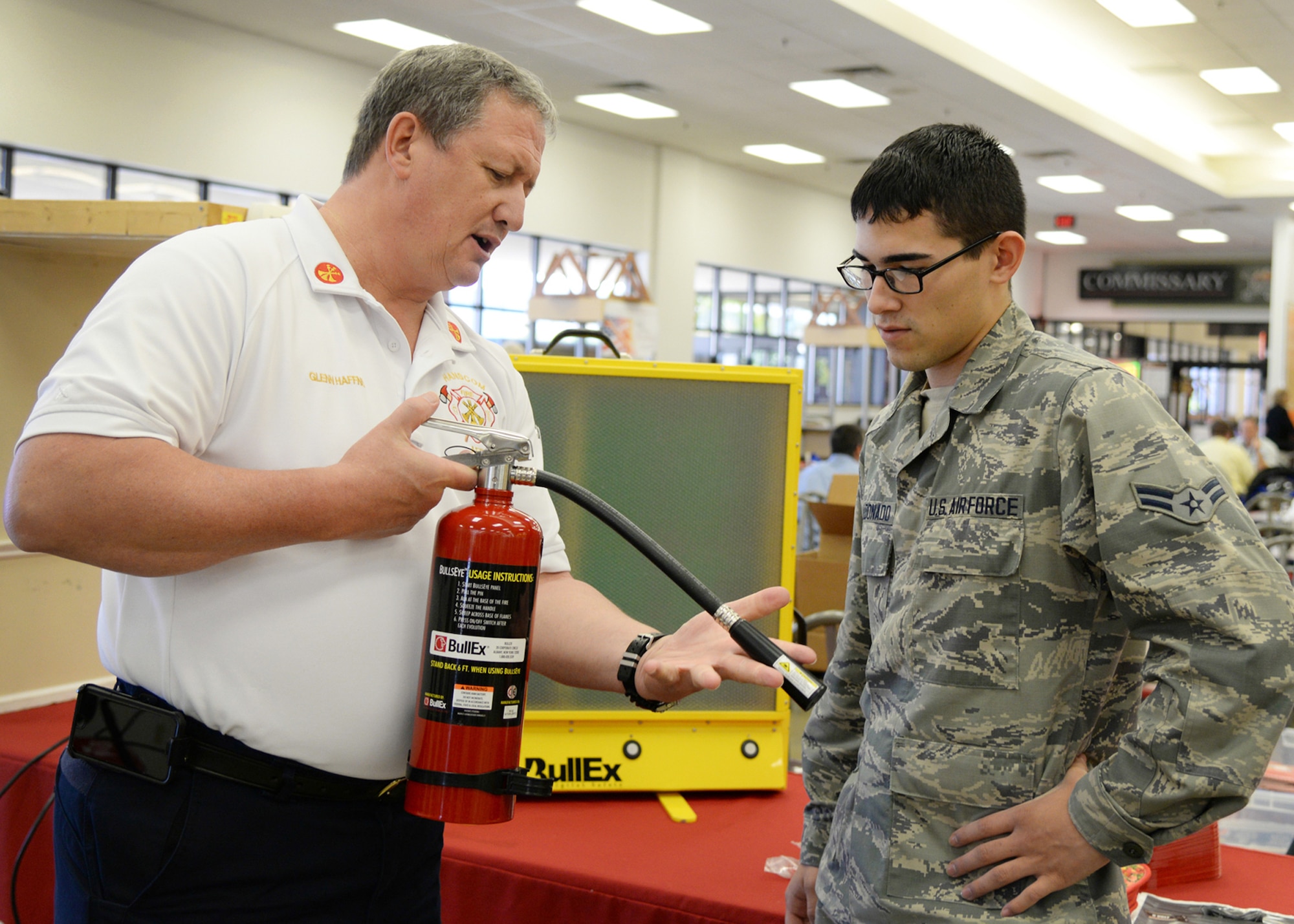 Glenn Haffner, Hanscom Fire Prevention and Life Safety chief, demonstrates to Airman 1st Class Alfredo Maldonado, 66th Force Support Squadron technician, the proper use of a fire extinguisher during a Fire Prevention Week activity at the Army and Air Force Exchange Service Oct. 7. Throughout the week, Hanscom's Fire Emergency Services team hosted activities at the Child Development Center, Hanscom Primary School and the Exchange to raise fire prevention awareness in the community. (U.S. Air Force photo by Linda LaBonte Britt)