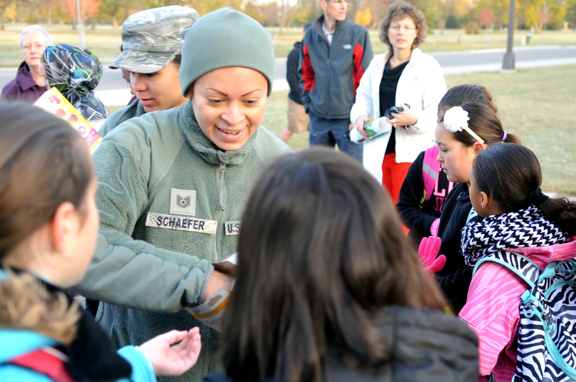 Tech. Sgt. Sara Schaefer, 319th Medical Support Squadron, hands out fruit snacks to children who participated in National Walk or Ride to School Day Oct. 7, 2015. The occasion was meant to encourage children and parents to talk about pedestrian safety. (U.S. Air Force photo/Staff Sgt. Susan L. Davis)