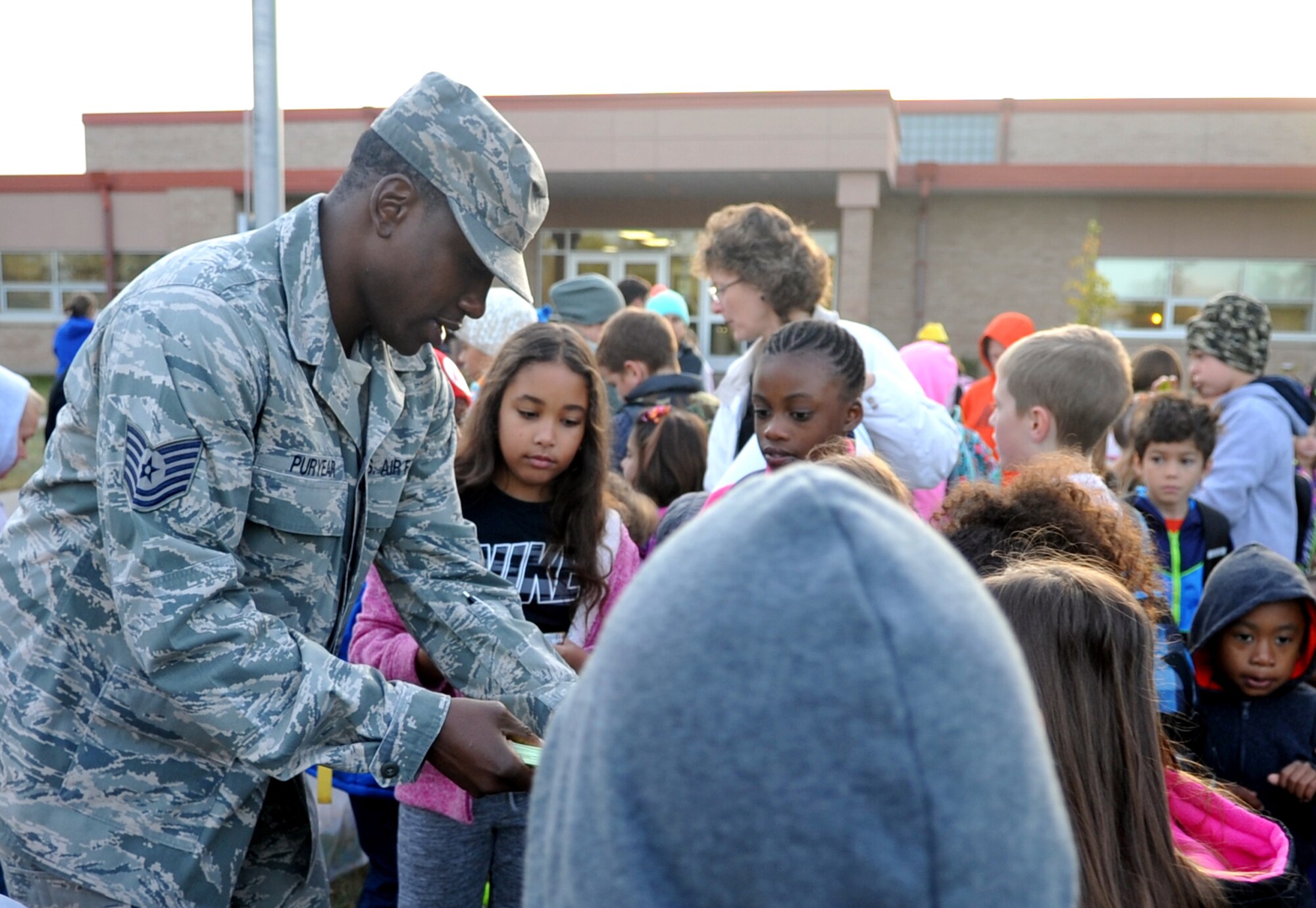 Tech. Sgt. Benjamin Puryear, 69th Maintenance Squadron, hands out prizes to children who participated in National Walk or Ride to School Day Oct. 7, 2015. The occasion was meant to encourage children and parents to talk about pedestrian safety. (U.S. Air Force photo/Staff Sgt. Susan L. Davis)