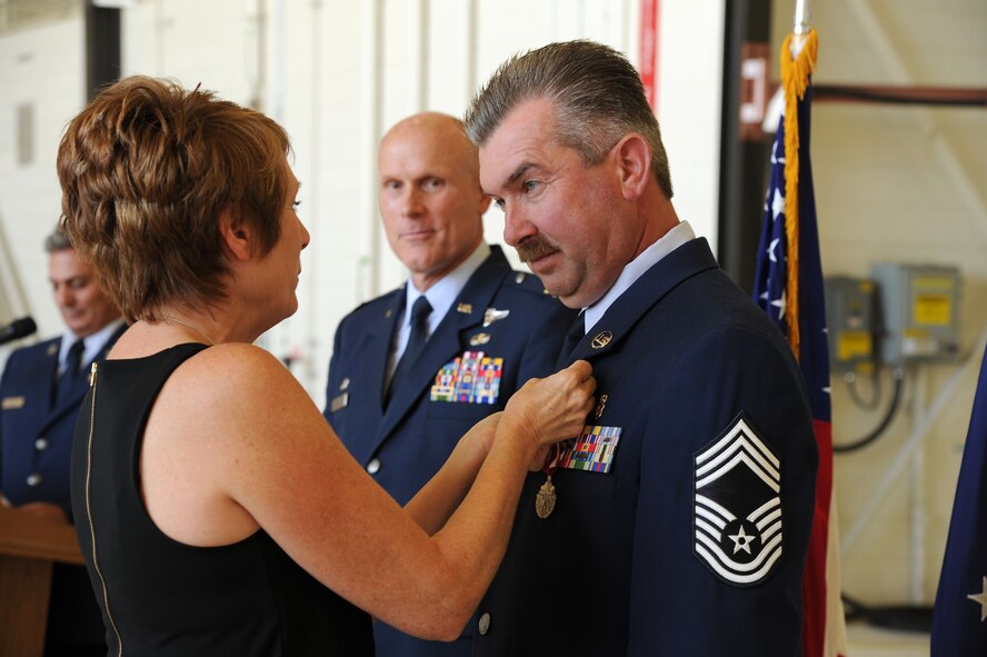 PETERSON AIR FORCE BASE, Colo. – Adrina Weicher presents her husband, Chief Master Sgt. Gregory Weicher, with a retirement pin during his retirement ceremony Oct. 3, 2015 here.  Weicher was the 302nd Aeromedical Staging Squadron superintendent. (U.S. Air Force photo/Senior Airman Amber Sorsek)