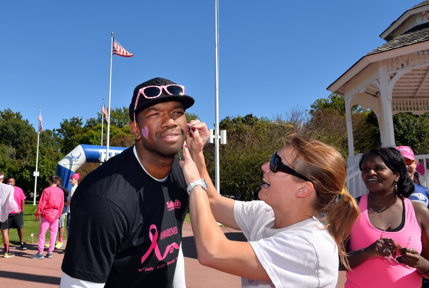 Staff Sgt. James McLean, 55th Wing Safety, gets his face painted by Marie Griffin, 55th WG Safety, Oct. 2, prior to running in a 5K for breast cancer awareness on the Offutt Air Force Base, Neb., parade grounds.  Runners were encouraged to wear pink and partake in face painting in order to make the run more festive.  (U.S. Air Force photo by Josh Plueger/Released)