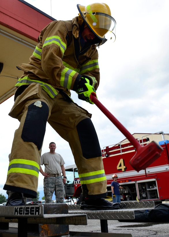 U.S. Air Force Maj. Jason Caranta, 31st Civil Engineer Squadron operations flight commander, hammers a metal slab during Fire Prevention Week, Oct. 7, 2015, at Aviano Air Base, Italy. Teams competed in in a fire combat challenge with obstacles that simulate challenges firefighters may experience while on the job.. (U.S. Air Force photo by Airman 1st Class Cary Smith/Released)