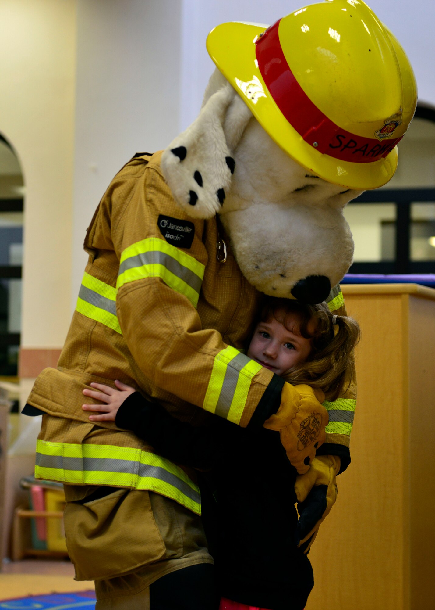 Sparky the fire dog hugs Sofia Ewing during Fire Prevention Week, Oct. 6, 2015, at Aviano Air Base, Italy. Sparky the fire dog visited the library during toddler reading and the Child Development Centers to teach children about fire safety. (U.S. Air Force photo by Airman 1st Class Cary Smith/Released)