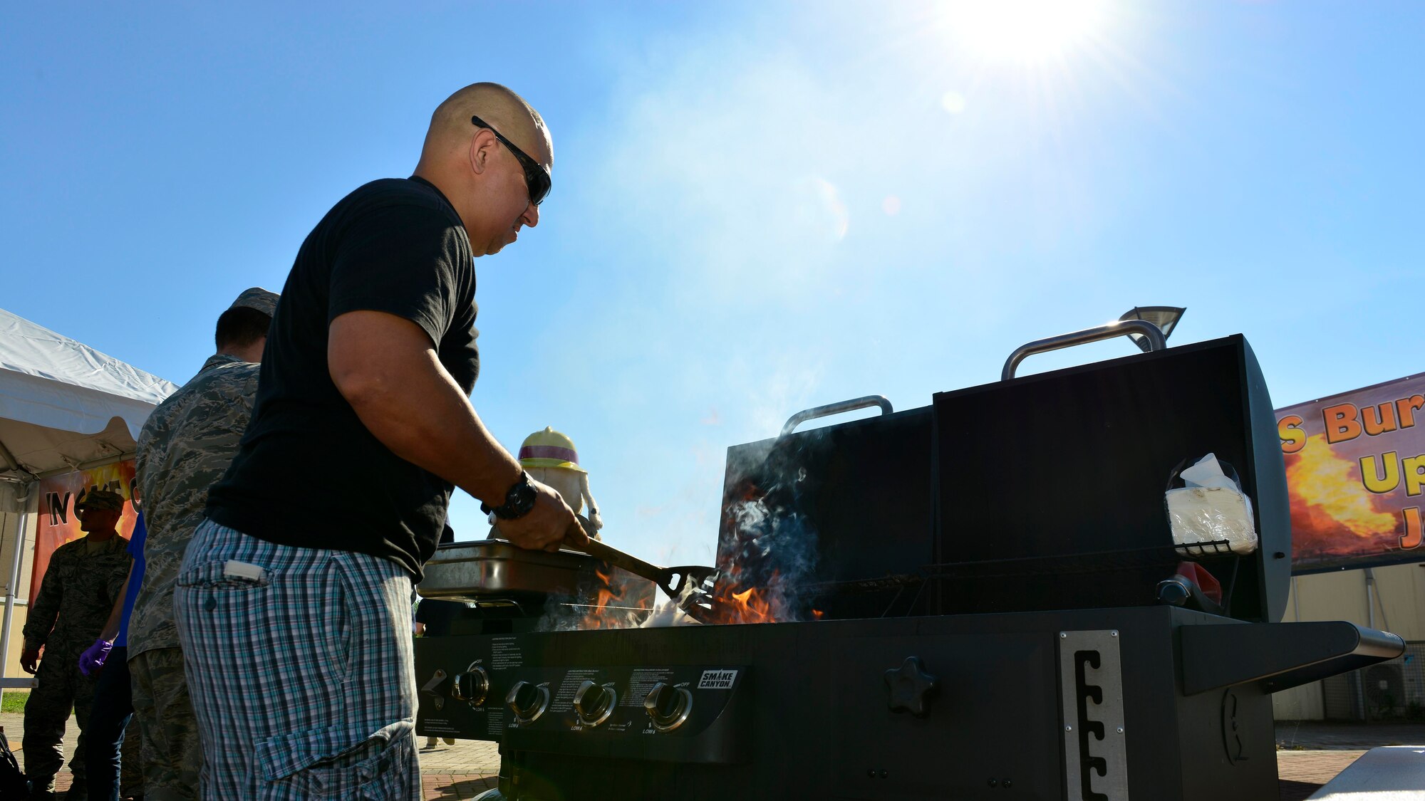 U.S. Air Force Master Sgt. Angus Adolpho, 31st Civil Engineer Squadron Fire Department assistant chief of operations, grills burgers and hotdogs during Fire Prevention Week, Oct. 5, 2015, at Aviano Air Base, Italy. The weeklong events promoted safety precautions to help prevent fires. (U.S. Air Force photo by Airman 1st Class Cary Smith/Released)