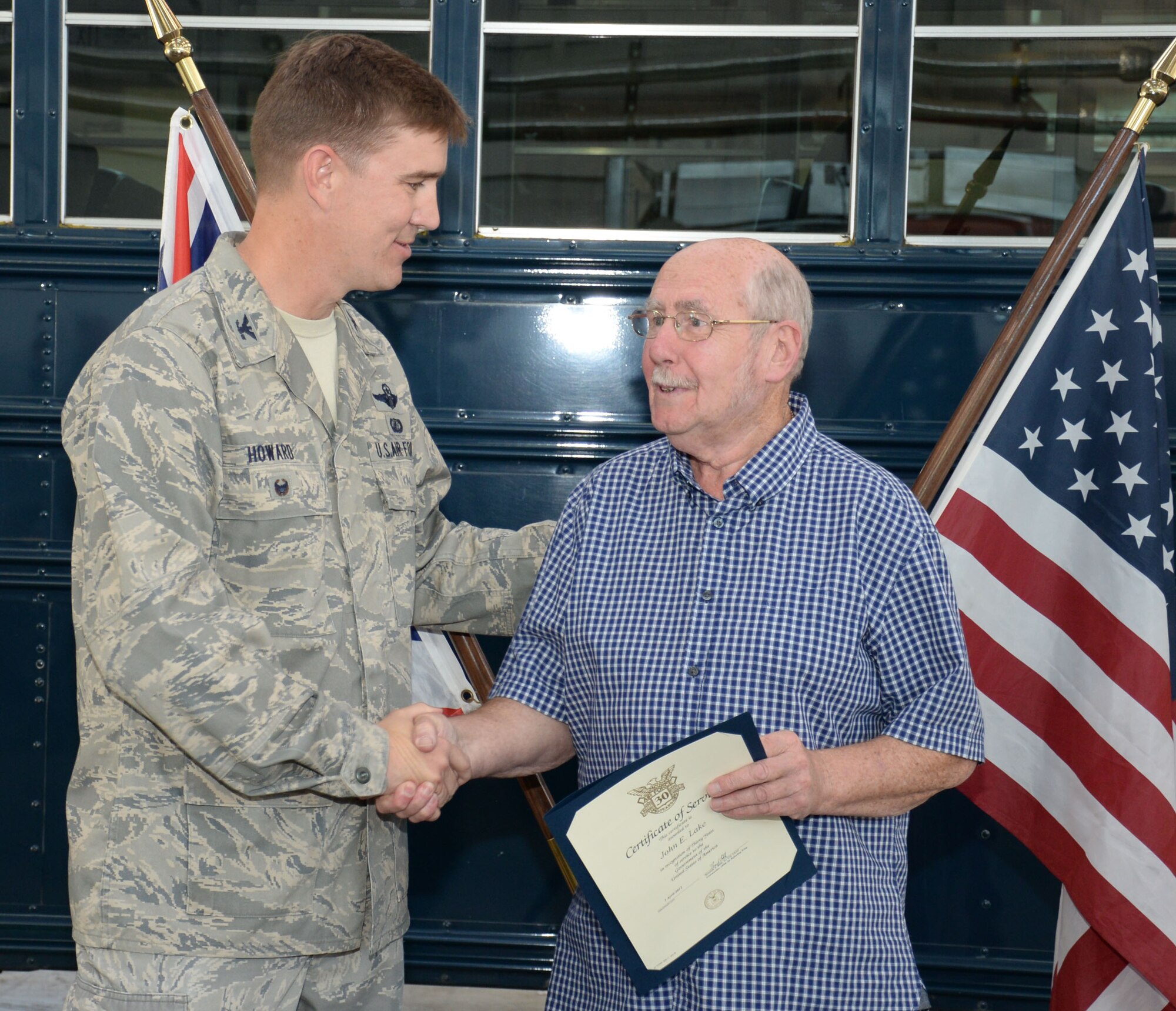U.S. Air Force Col. John Howard, left, 100th Air Refueling Wing vice commander, presents John Lake, retired Ministry of Defence vehicle operator, with a certificate of service to the United States of America following more than 30 years of service Oct. 1, 2015, at RAF Mildenhall, England. Howard presented Lake with a 30-year certificate of service and pin for his unwavering dedication to the U.S. Air Force mission on both RAF Mildenhall and RAF Lakenheath. (U.S. Air Force photo by Gina Randall/Released)