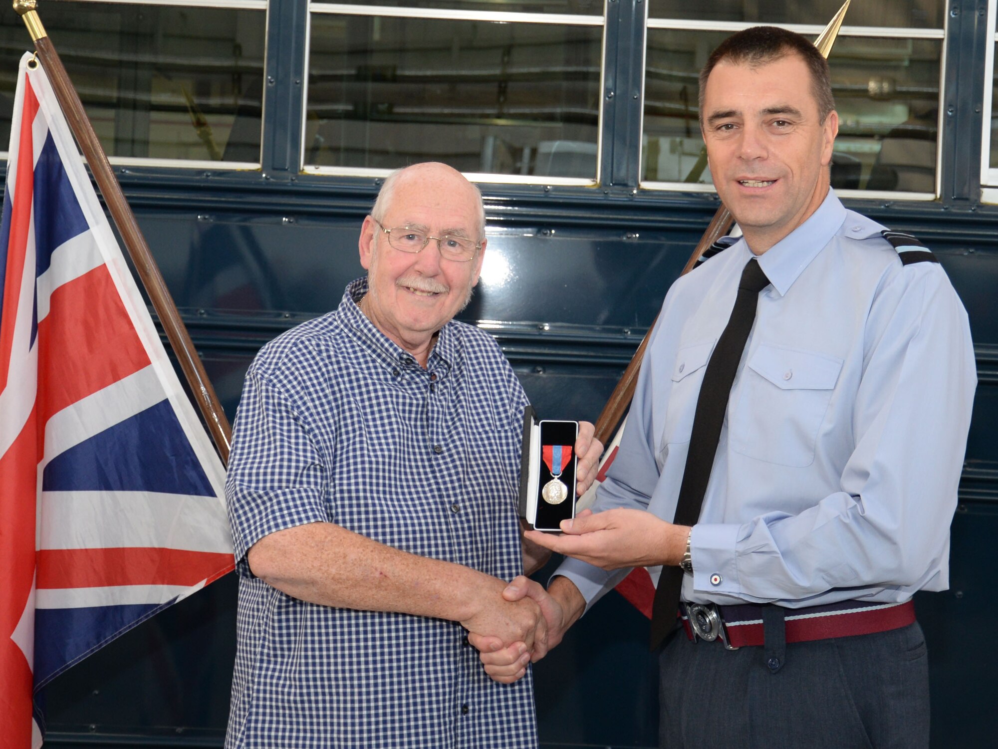 Air Vice Marshal Tim Bishop, right, Air Officer Commanding 38 Group, presents John Lake, retired Ministry of Defence vehicle operator, with the Imperial Service Medal on behalf of Her Majesty The Queen following 32 years of service Oct. 1, 2015, at RAF Mildenhall, England. According to Steven Randall, 100th Logistics Readiness Squadron distribution manager, Lake retired with an impeccable record throughout his career with the 100th Logistics Readiness Squadron. (U.S. Air Force photo by Gina Randall/Released)