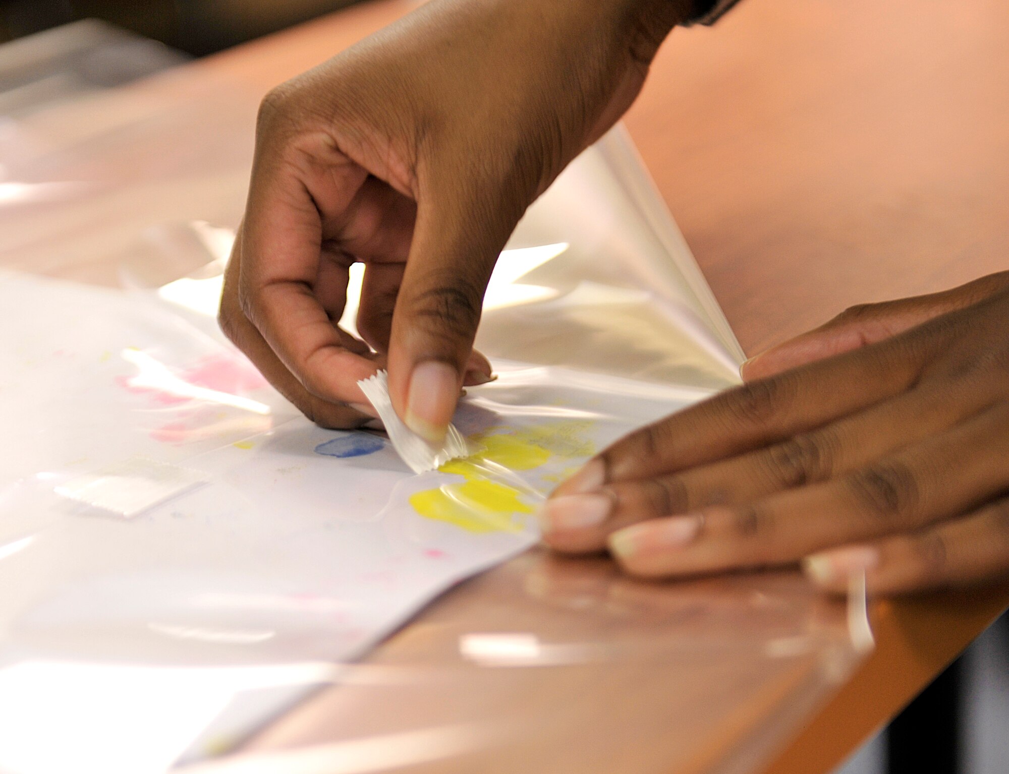 U.S. Air Force Senior Airman Jhodeci Redmon, 18th Maintenance Group delicate scheduler, tapes wrapping on artwork Oct. 7, 2015, on Kadena Air Base, Japan. The Kadena Special Olympics Art Exhibit will be held at Main City Shopping Mall San-A in Uruma City, and will run from Oct. 15-18. The exhibit will include 273 works of art created by special needs students from elementary and junior high schools in Okinawa City, Chatan, Kadena Town and Okinawa Prefectural special education schools. (U.S. Air Force photo by Naoto Anazawa)